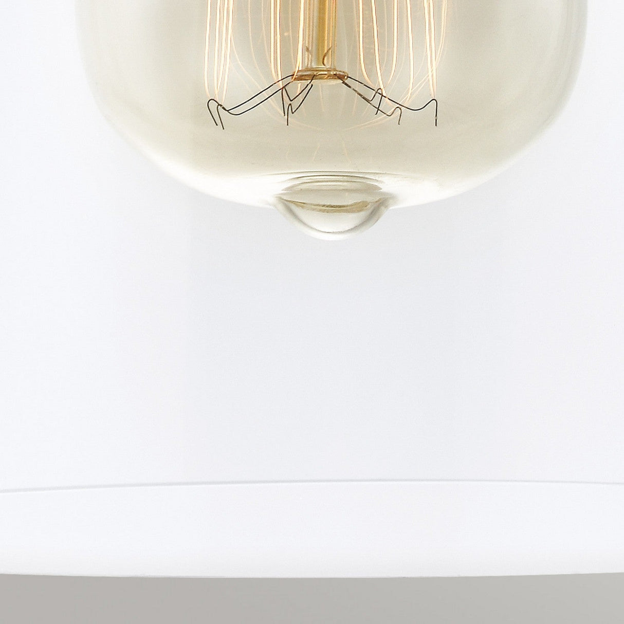 A close-up of the Matrimonio 1 Light Mini Pendant in Driftwood/Dark Weathered Zinc reveals a vintage-style Edison light bulb with visible filament against a plain white background. This elegant piece captures the rustic charm through its intricate filament wiring inside the clear glass bulb.