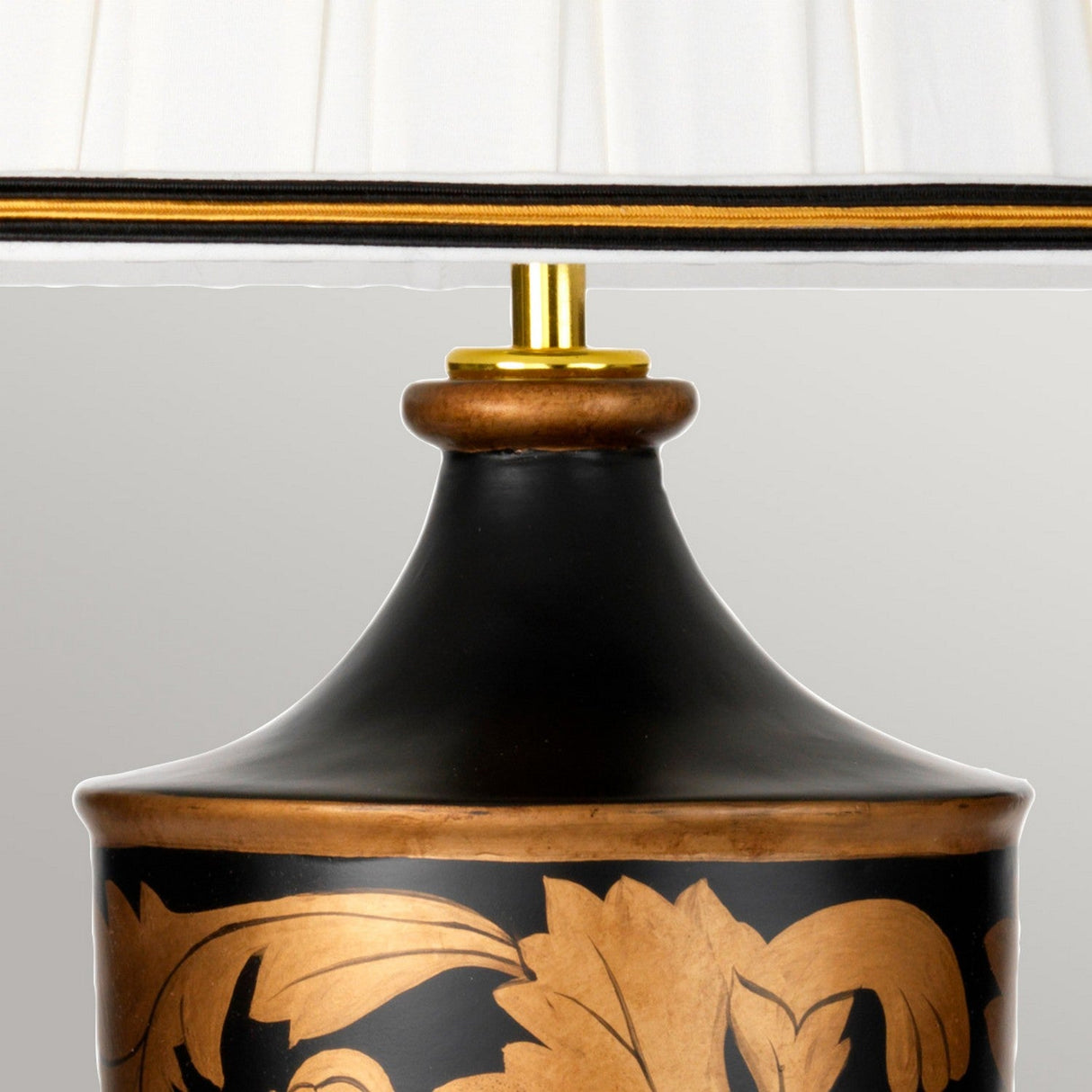 A close-up of the Narbonne Table Lamp - Black & Gold highlights its elegance with a cream pleated shade, while the base exhibits a Black & Gold floral pattern and a golden neck, contributing to the sophistication and classic design of this refined piece.