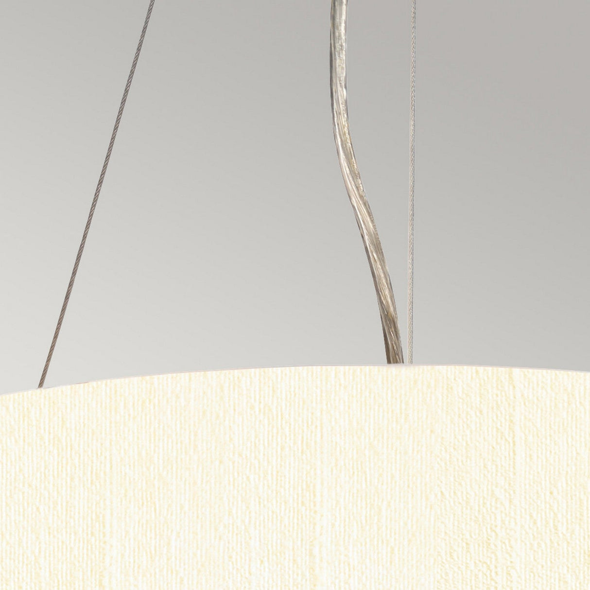 Close-up of the Pearce 14" Pendant Light with an aged brass finish and an ivory textured faux silk shade. It hangs elegantly from the ceiling by two thin wires, with a silver-colored cable set against a light gray background.