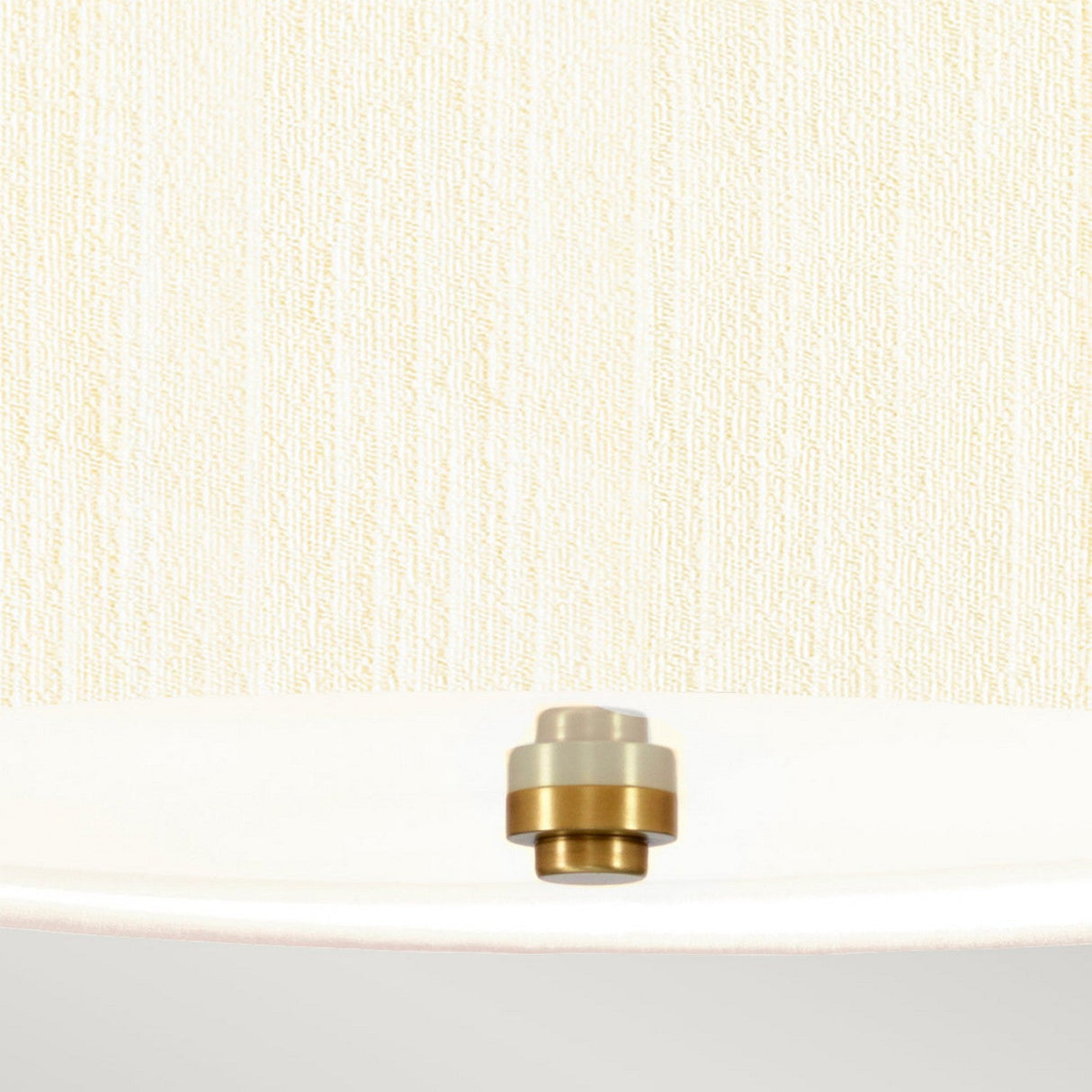 A minimalist image featuring an aged brass bolt resting on the edge of a white surface against a textured cream-colored background captures elegance similar to the Pearce 14" Pendant Light with an ivory shade.