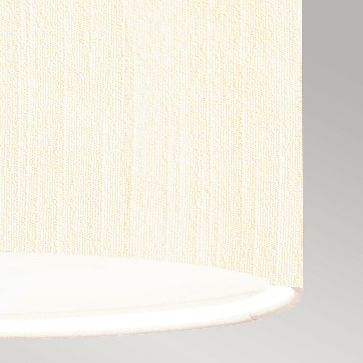 Close-up of the Pearce 14" Pendant Light featuring an aged brass fixture and an ivory textured fabric shade, partially covering a smooth, circular white surface, set against a light gray background.