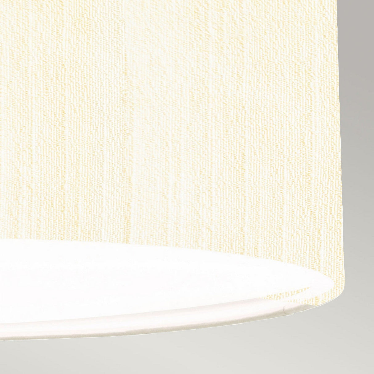 Close-up of an ivory-textured, faux silk Pearce 18" Pendant Light - Aged Brass against a light gray background. The fabric pattern and subtle curves of the shade's bottom edge are visible, beautifully complemented by aged brass accents.