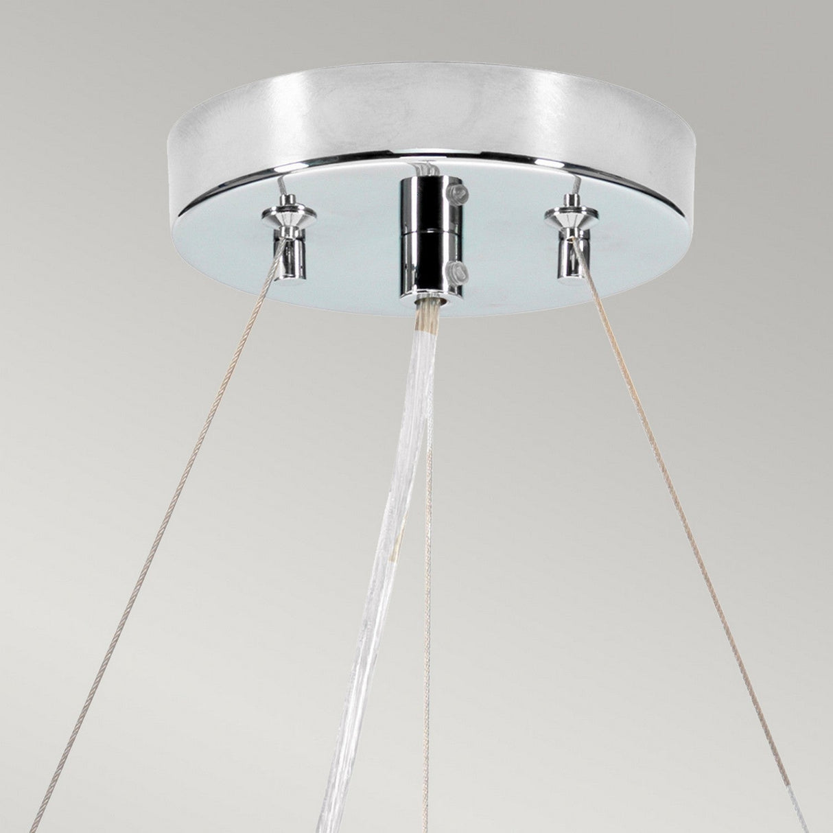 A contemporary ceiling-mounted fixture featuring a sleek, polished chrome design, reminiscent of the Pearce 18" Pendant Light. Three thin cords support a central nozzle that emits a steady stream of water, evoking the elegance of an ivory-shaded pendant light against a neutral backdrop.