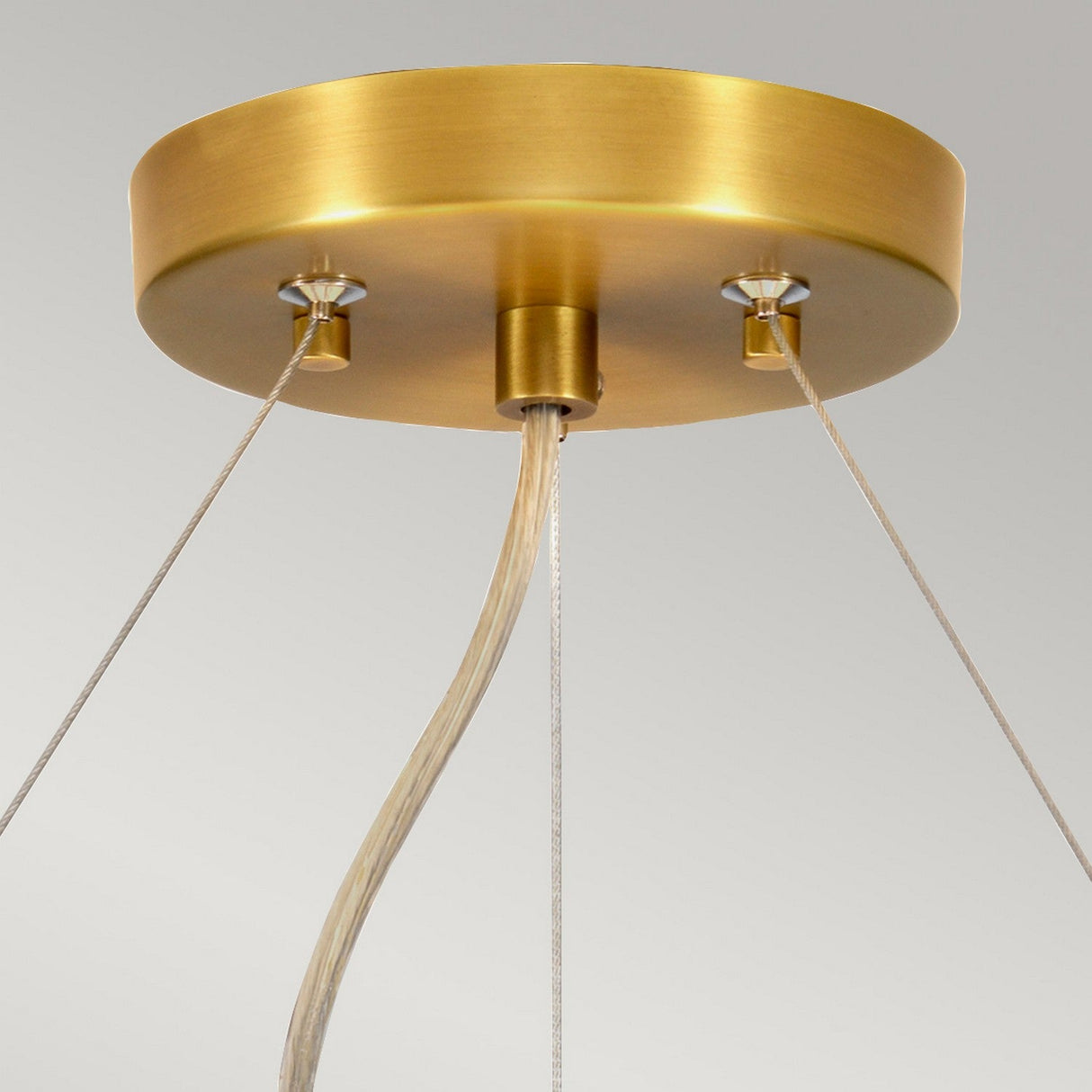 A close-up of the Pearce 22" Pendant Light showcases its round, aged brass canopy. Three cables elegantly extend downward, harmonizing with the sophisticated faux silk ivory shade, all set against a plain gray background.