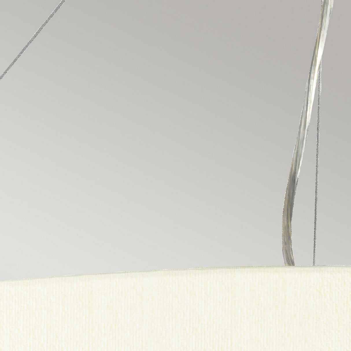 A close-up of the Pearce 30" Pendant Light reveals its sleek, modern design in a minimalistic setting. The aged brass finish paired with its curved ivory shade stands out against a simple gray background, crafting a contemporary and elegant aesthetic.