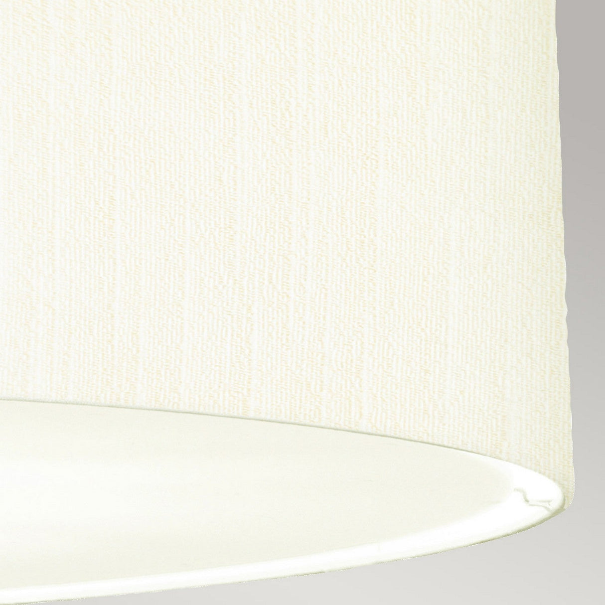 Close-up of the Pearce 30" Pendant Light, featuring an ivory faux silk shade with a subtle textured pattern, set against a gray background. The bottom edge curves slightly, revealing the elegant interior of this pendant light in aged brass.