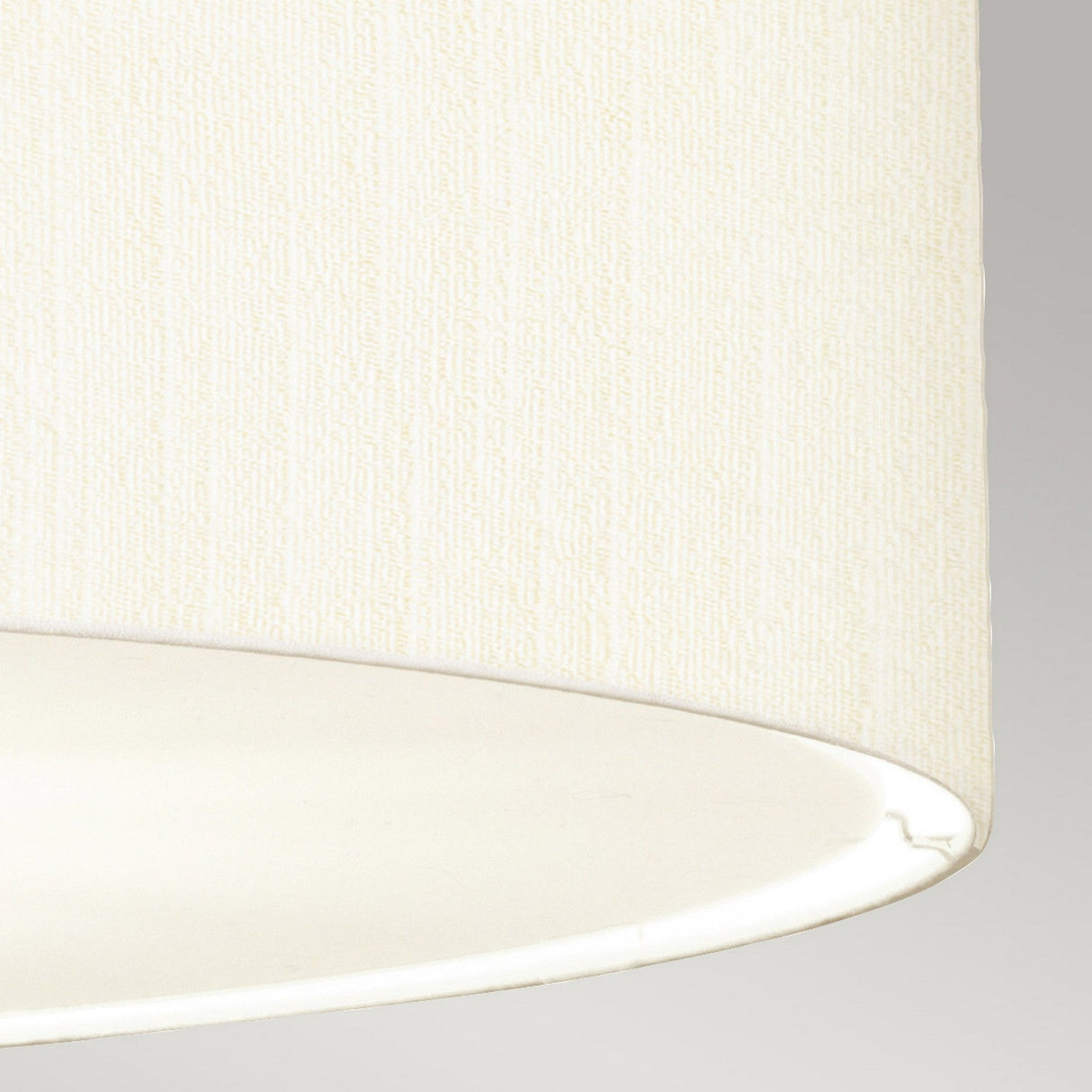 Close-up of the Pearce 34" Pendant Light with an ivory faux silk lampshade featuring a textured surface. The cylindrical shape gently diffuses light from its bottom opening, set against a simple gray background that highlights the elegance of this lighting fixture in aged brass.