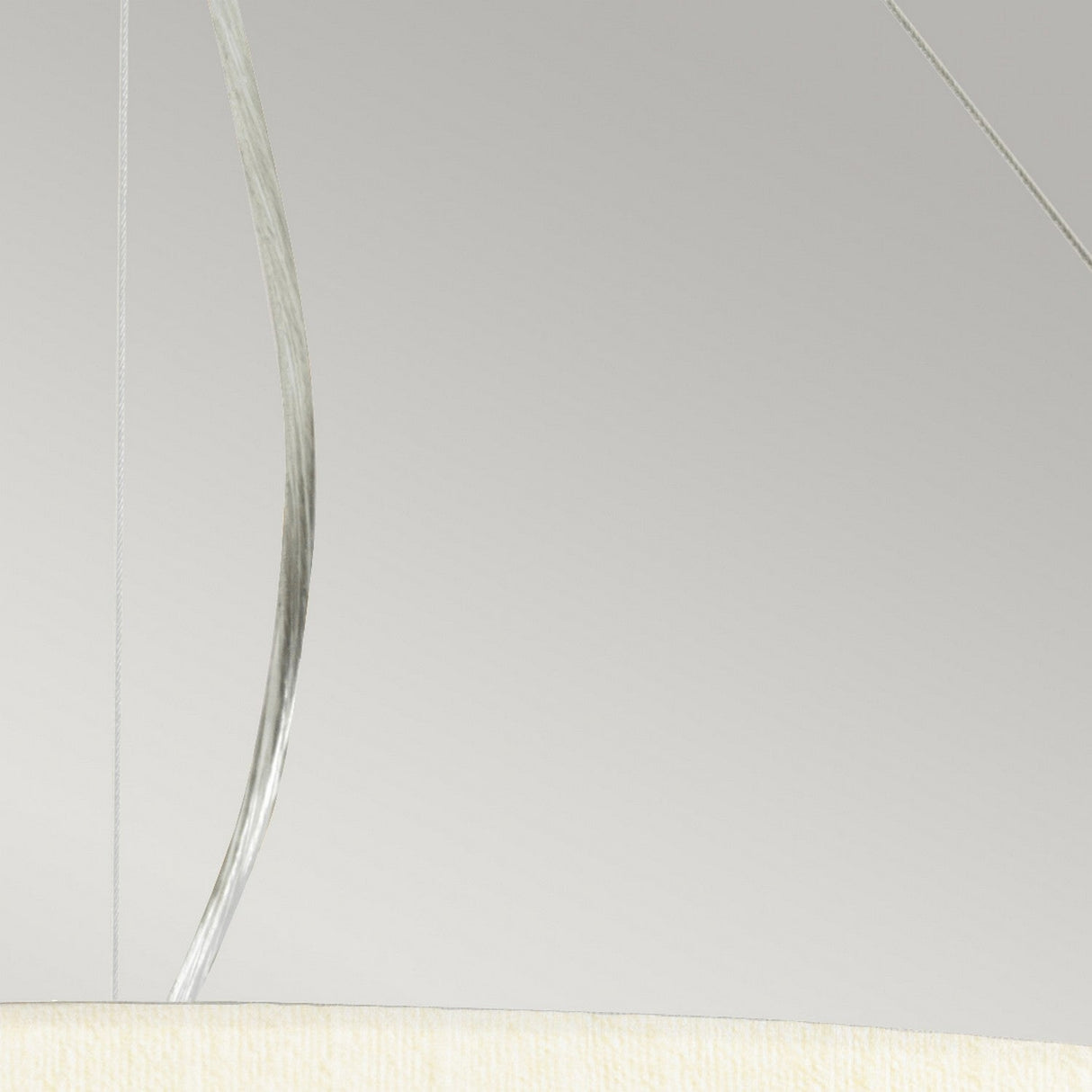 A minimalist image features a section of the Pearce 34" Pendant Light in polished chrome, highlighting its translucent thin wires against a plain, off-white background. The focus is on showcasing the simplicity and elegance of modern interiors.