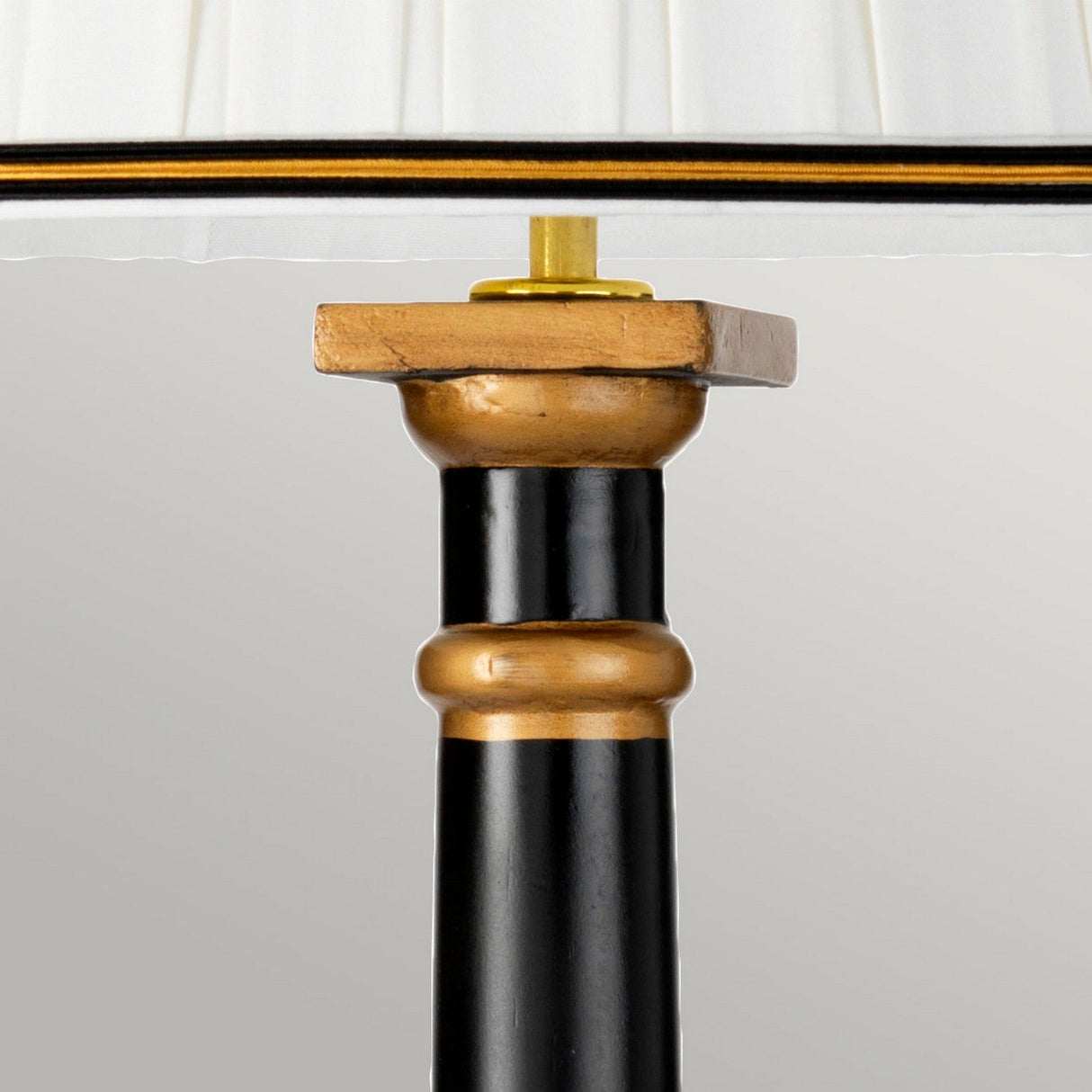 Close-up of the Peronne Table Lamp, showcasing its elegant tall empire shade and brass connector, complemented by a black and gold decorative pole. The design exudes modern sophistication.