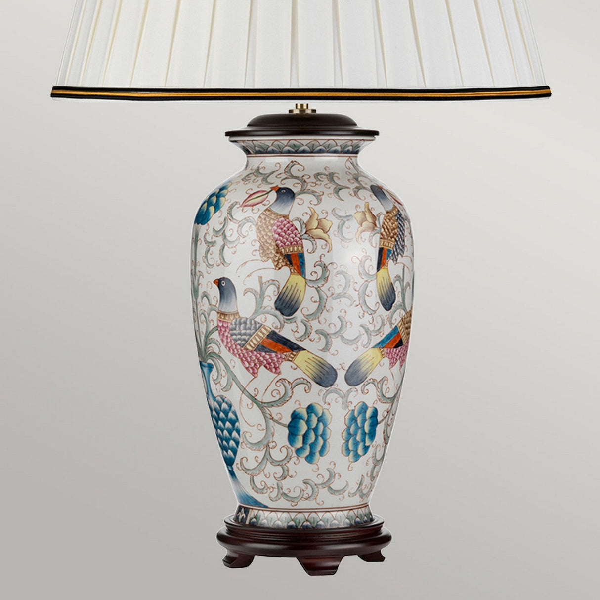 Introducing the Ping Table Lamp in cream, showcasing a porcelain base adorned with hand-painted birds and floral designs. It features an elegant ivory cotton box pleat shade, complemented by a sturdy dark wooden stand.