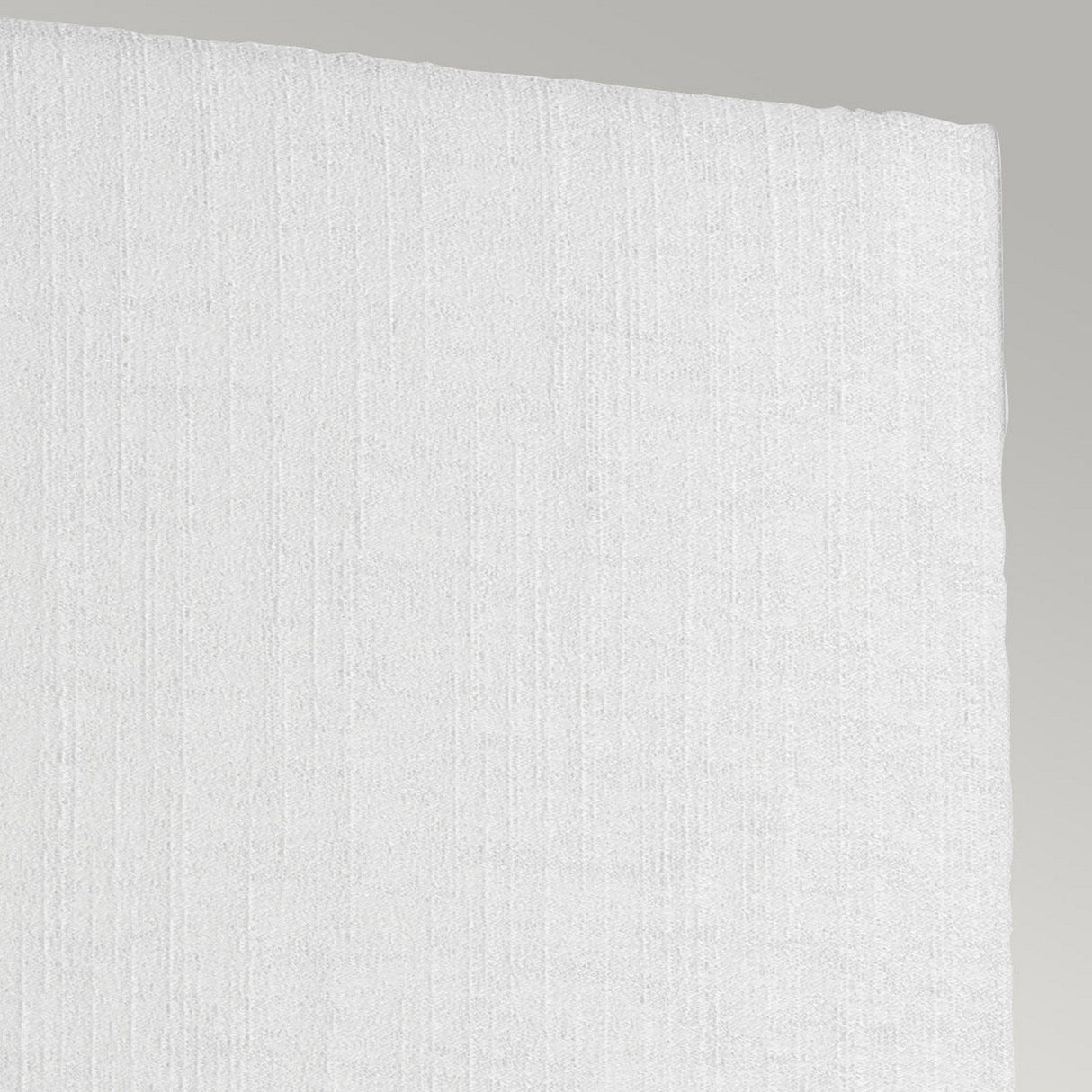 Close-up of a white textured fabric featuring subtle vertical lines, similar to the delicate finish of a faux silk shade. The fabric's edge elegantly contrasts with a plain, light gray background, evoking the elegance found in the Riley Medium Rectangular Wall Light - Aged Brass.