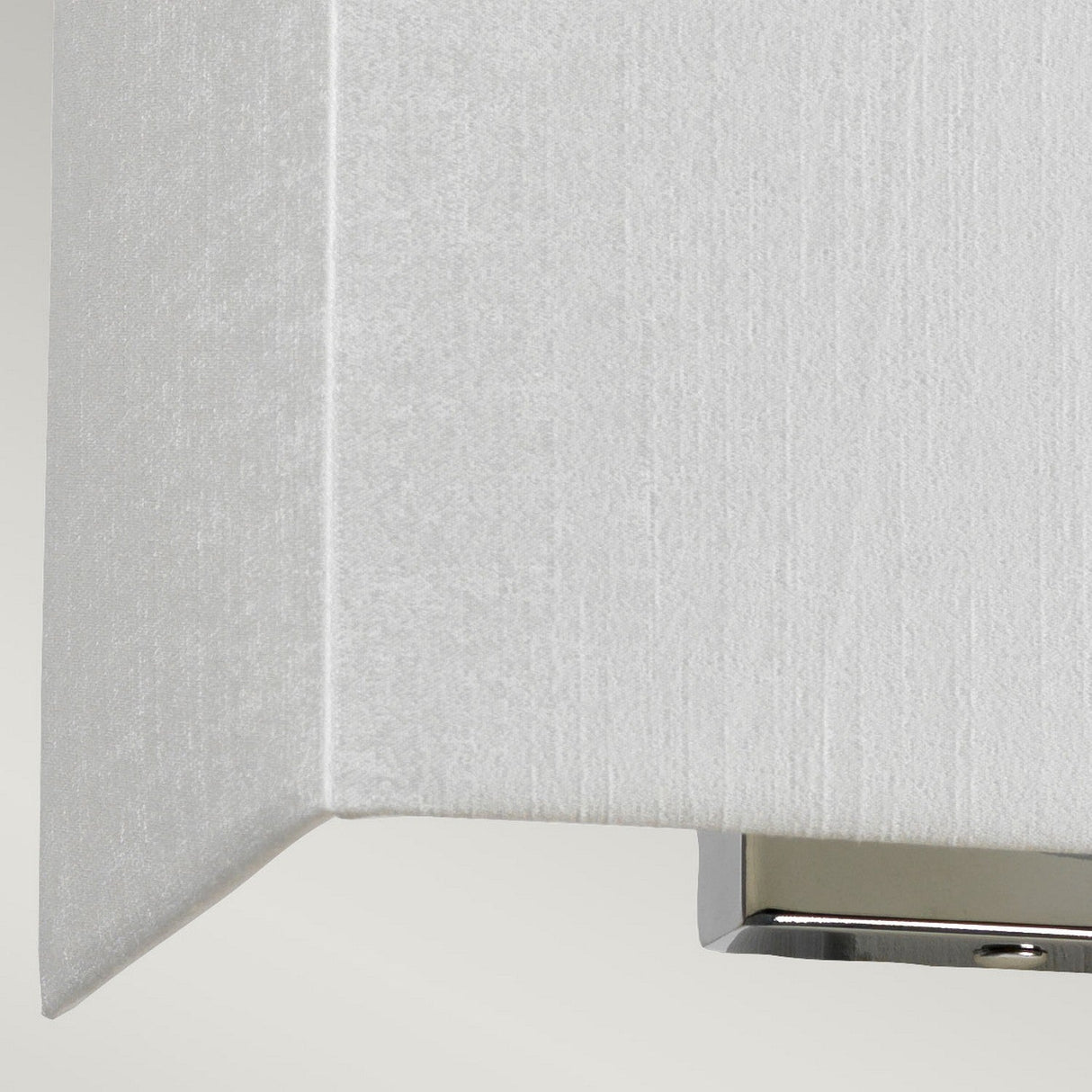 Close-up of the Riley Medium Rectangular Wall Light - Polished Chrome, featuring a neutral fabric shade. This contemporary fixture offers ambient lighting and showcases a sleek polished chrome finish along the bottom edge.