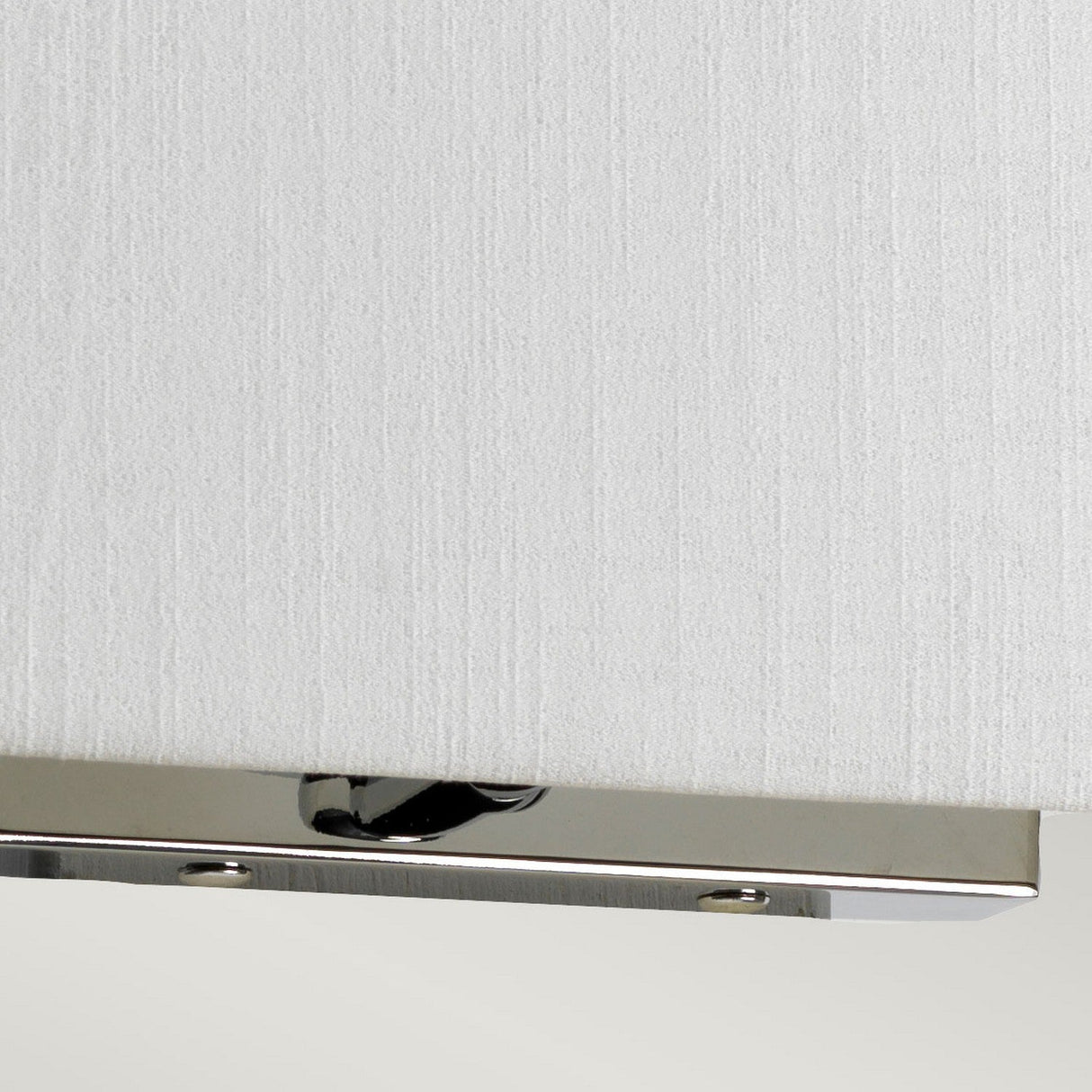 Close-up of the Riley Medium Rectangular Wall Light - Polished Chrome, showcasing its textured white shade and elegant polished chrome base. This modern fixture provides ambient lighting and is partially visible against a light gray background.