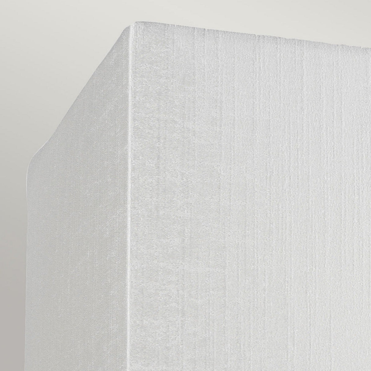 Close-up image of the Riley Small Rectangular Wall Light - Aged Brass, showcasing its soft, textured white corner against a light gray background. The fabric exhibit features a subtle vertical pattern reminiscent of faux silk shade, complementing its sophisticated aged brass finish.