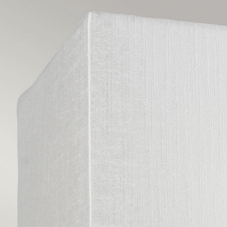 Close-up view of the corner of a textured white mattress set against a light gray background, subtly illuminated by the Riley Small Rectangular Wall Light in Polished Chrome, which casts gentle shadows.