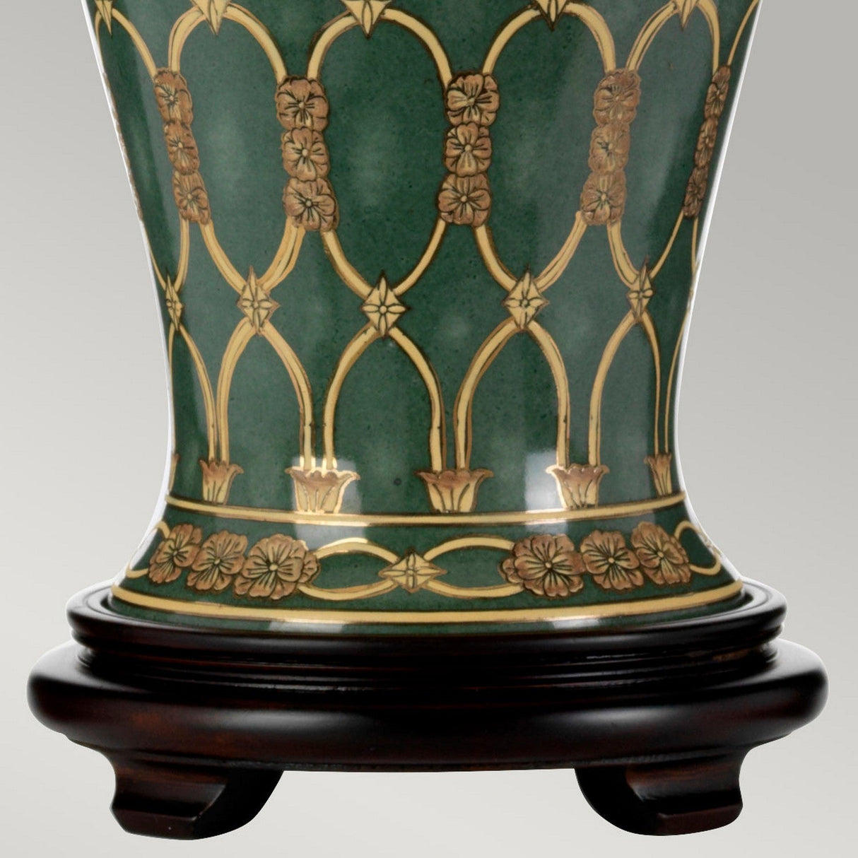The Sashi Table Lamp with a tall empire shade features a green base adorned with intricate gold patterns and touches of brown, all highlighting oriental craftsmanship. It is elegantly displayed on a dark wooden stand against a plain, light gray background.