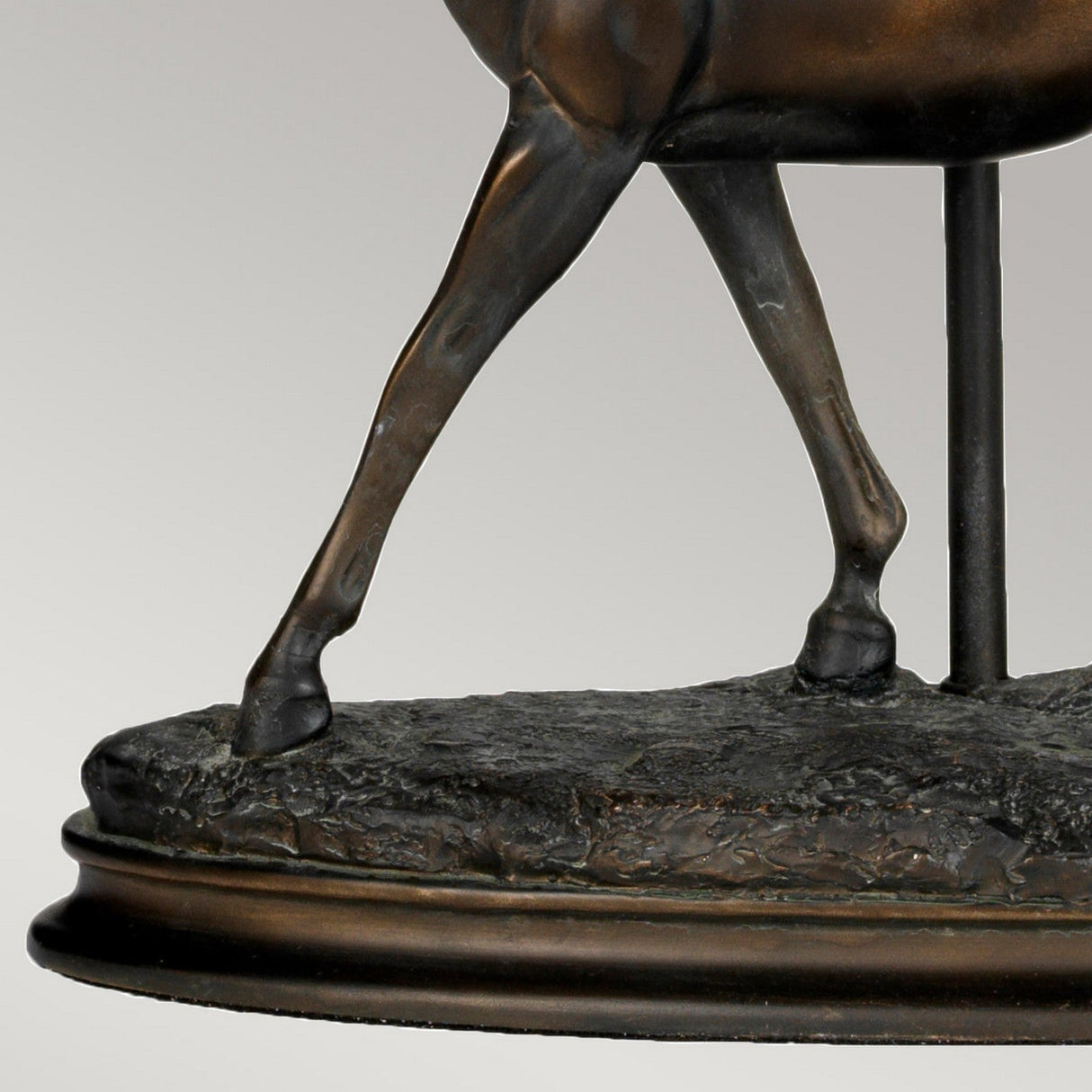 Close-up of the Spirit Table Lamp With Oval Shade in bronze patina, highlighting its exquisite finish. The lamp captures detailed craftsmanship reminiscent of an animal's musculature, possibly appealing to equestrian enthusiasts. Its oval-shaped shade features a smooth edge.