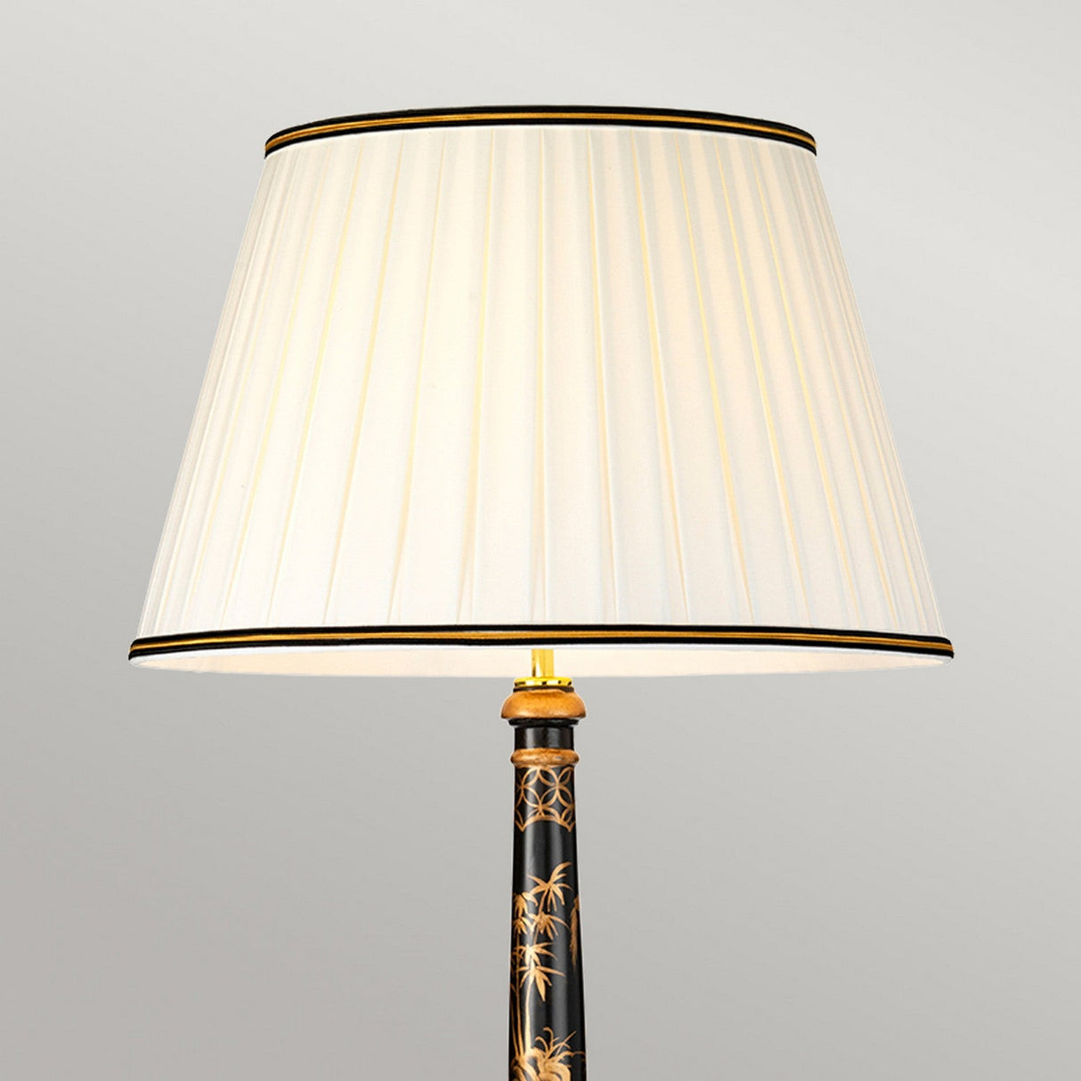 The Strasbourg Table Lamp With Tall Empire Shade - Black & Gold showcases a refined pleated white finish on its tall empire shade. The lamp's black ornate base is accentuated by sophisticated gold floral designs, elegantly contrasting with a plain light gray background.