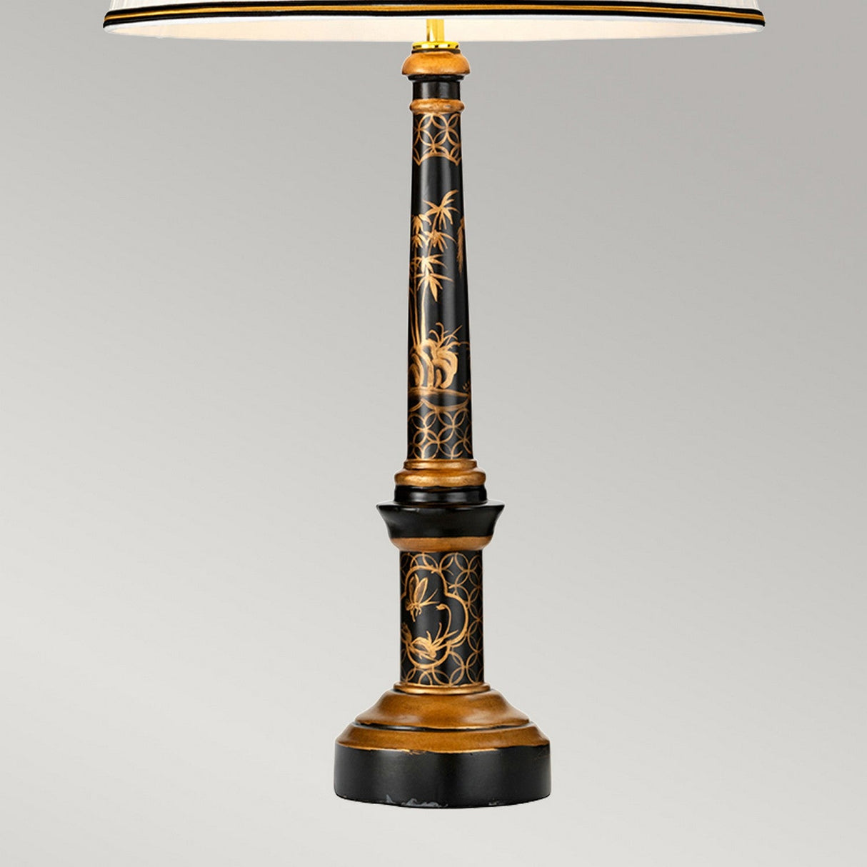 The Strasbourg Table Lamp With Tall Empire Shade - Black & Gold features a sleek, ornately crafted base in black and gold with intricate floral designs. It is elegantly complemented by a tall empire shade, set against a simple gray backdrop.