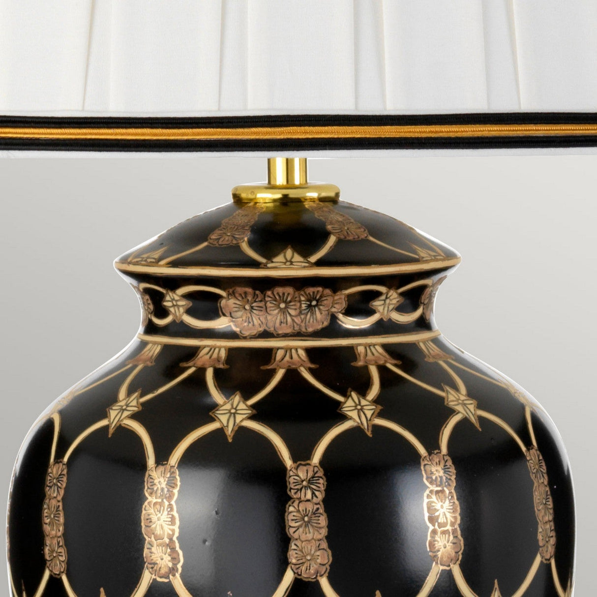 Featuring an elegant oriental ceramic vase design, the Taipei Table Lamp With Tall Empire Shade - Black & Gold showcases intricate gold floral patterns and geometric designs on a black base. It is adorned with a white pleated shade trimmed in black and gold, epitomizing sophisticated black and gold lighting.