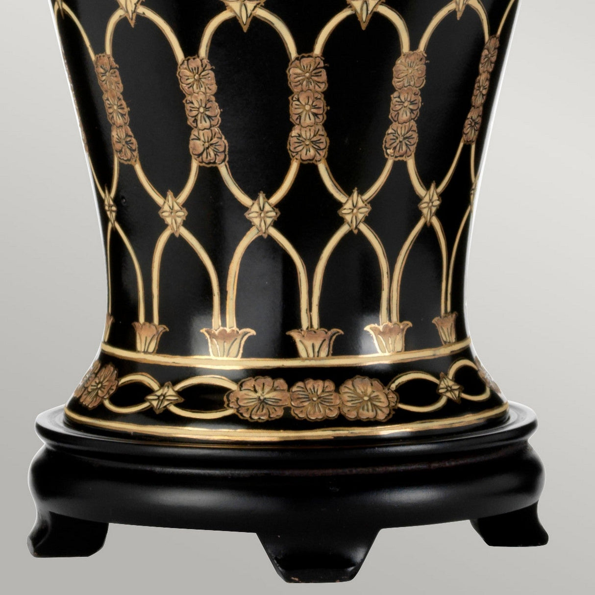 A close-up of a decorative vase in black with gold floral patterns and arching lines, reminiscent of the Taipei Table Lamp With Tall Empire Shade - Black & Gold. The intricate petal and star-like motifs elegantly catch the light, resembling the lamp's glow as it rests on a dark pedestal base.