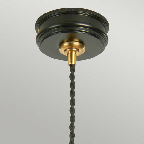 The Douille 1 Light Pendant in Black & Polished Brass is shown in a close-up view, featuring a round black canopy and a polished brass lamp holder with a twisted black cord hanging down. This fixture is set against a plain white ceiling, creating a striking contrast that highlights its elegant simplicity.