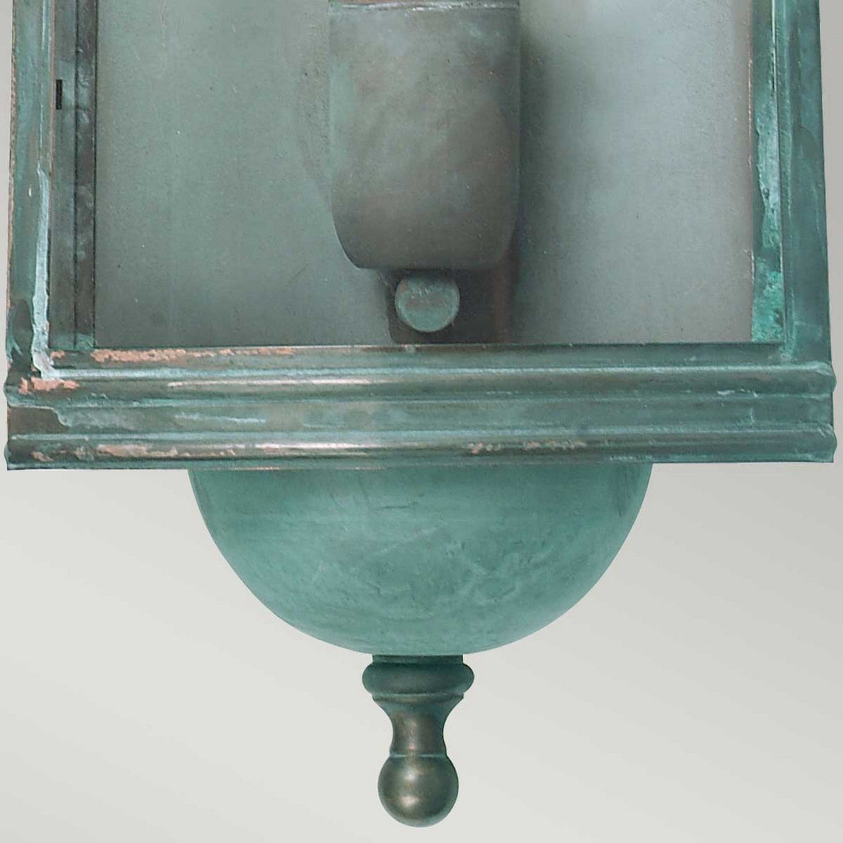 The Downing Outdoor Wall Light in turquoise features a weathered architectural detail with a rounded finial at the bottom and rectangular elements above. Resembling a pre-Georgian lantern, this piece showcases an aged metal patina that exudes a minimalist design with classical influence.