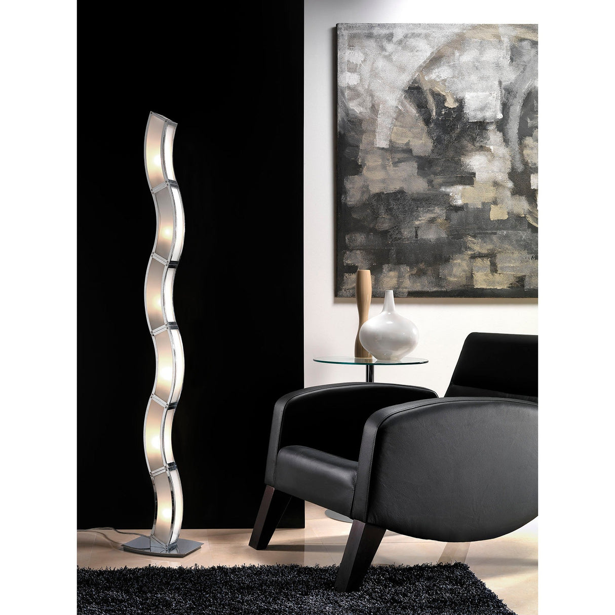 A modern living room features the Duna 6 Light Floor Lamp in chrome and white acrylic, a black armchair, a glass side table with two vases, a textured black rug, and an abstract monochrome painting on the wall.