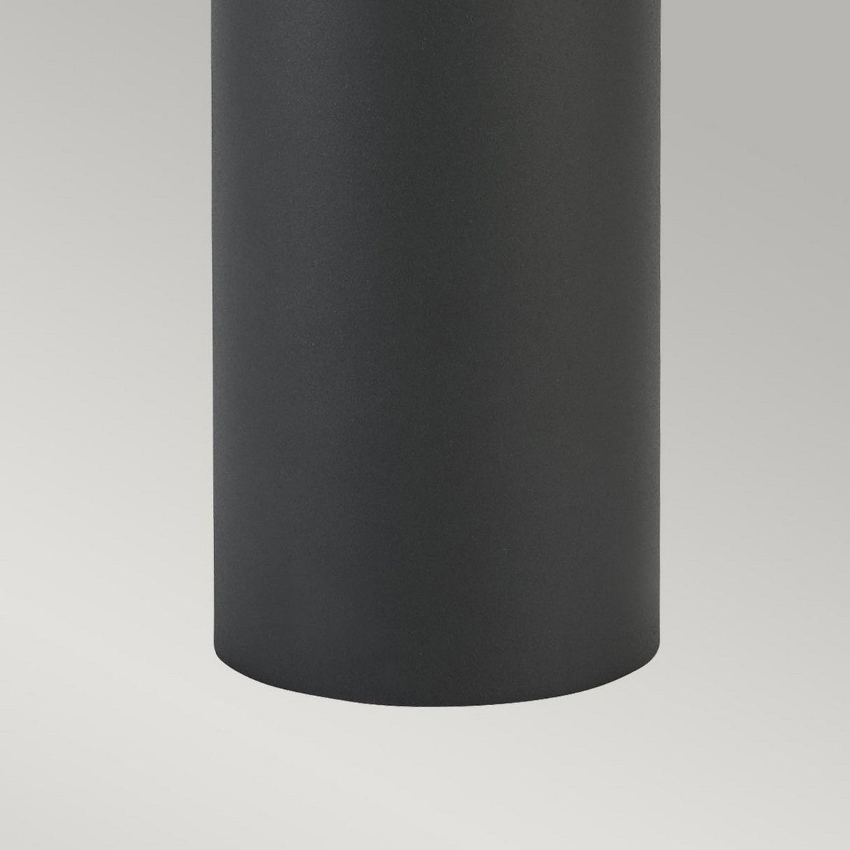 Close-up of the lower section of a cylindrical item, similar to the Egersund LED Short Bollard - Graphite, featuring a smooth, dark surface against a light background. The cylinder's matte texture makes it ideal for energy-efficient outdoor lighting.