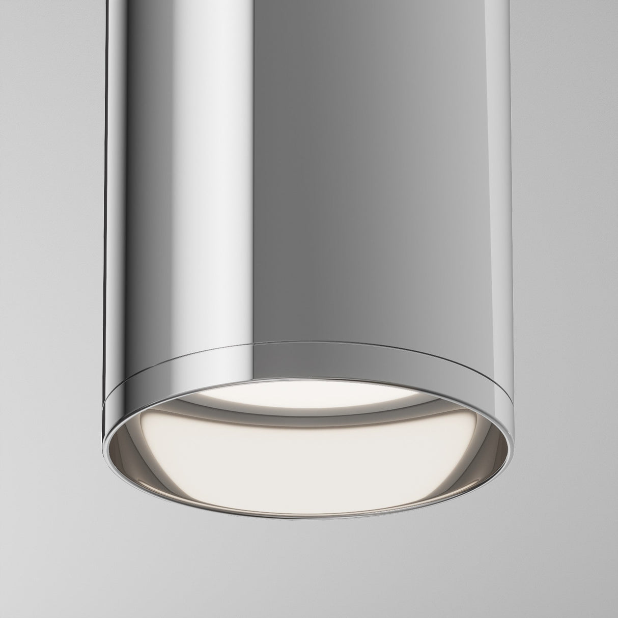 A close-up shows the Focus Fixed Round Surface Mounted Downlight in chrome, emitting a soft, warm glow from its base against a white background.