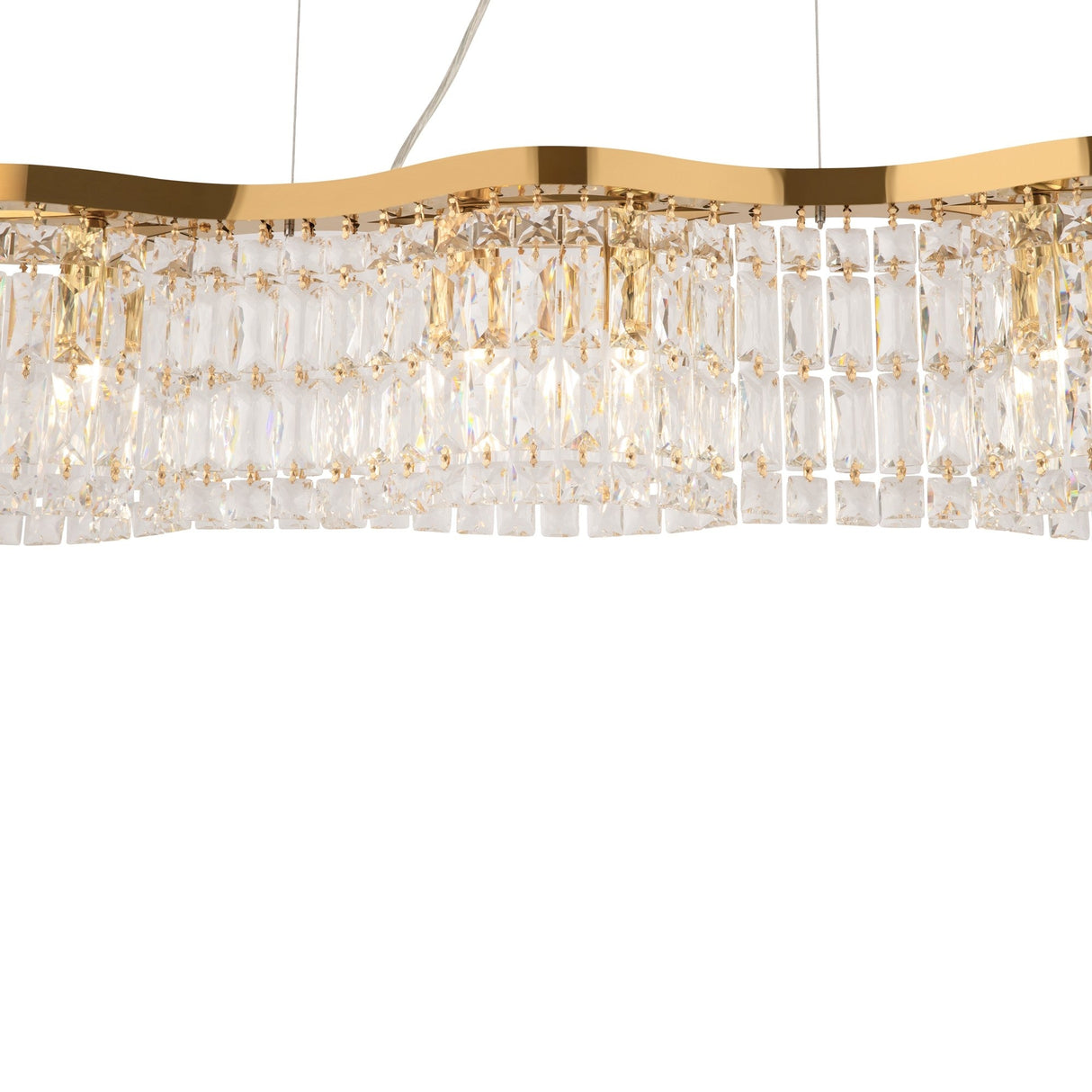 The Dune 6 Light Island Suspension - Gold chandelier features a wave-shaped gold frame with vertically hanging rectangular crystal prisms that reflect light beautifully, creating an elegant and luxurious look. It is suspended by cables, enhancing its modern design.
