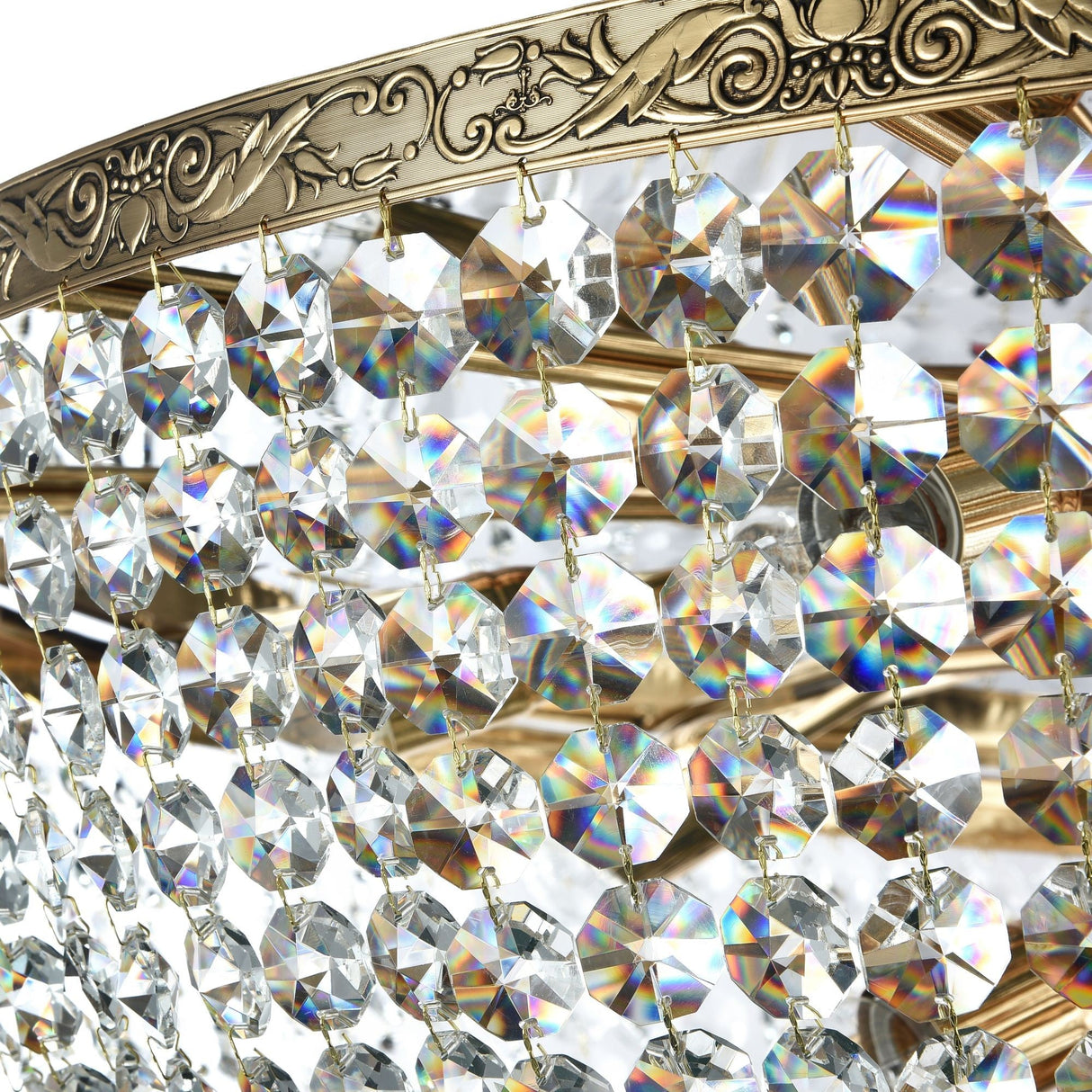 The Palace 18 Light Crystal Chandelier - Gold features a luxurious design with multiple faceted crystal pendants hanging from an engraved brass frame in antique gold, creating a beautiful display of shimmering colors throughout the room.