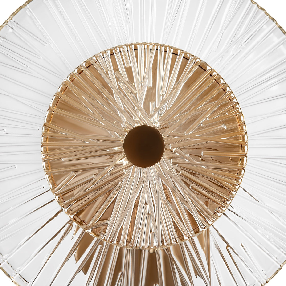 A close-up of the Aster Wall Light in gold features a central brown disc accentuated by clear, textured glass rods extending outward, forming a dynamic geometric pattern. The ambient light emits a warm glow against a plain white background.
