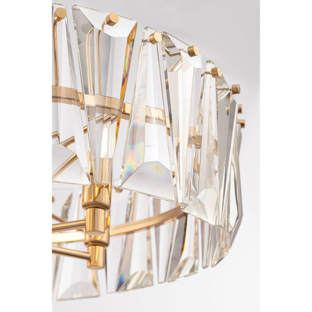 The Puntes 6 Light Chandelier - Gold is a luxurious fixture with triangular prisms on a gold metal frame. The crystals reflect light, creating a colorful spectrum, while its elegant and contemporary design emphasizes sophistication.