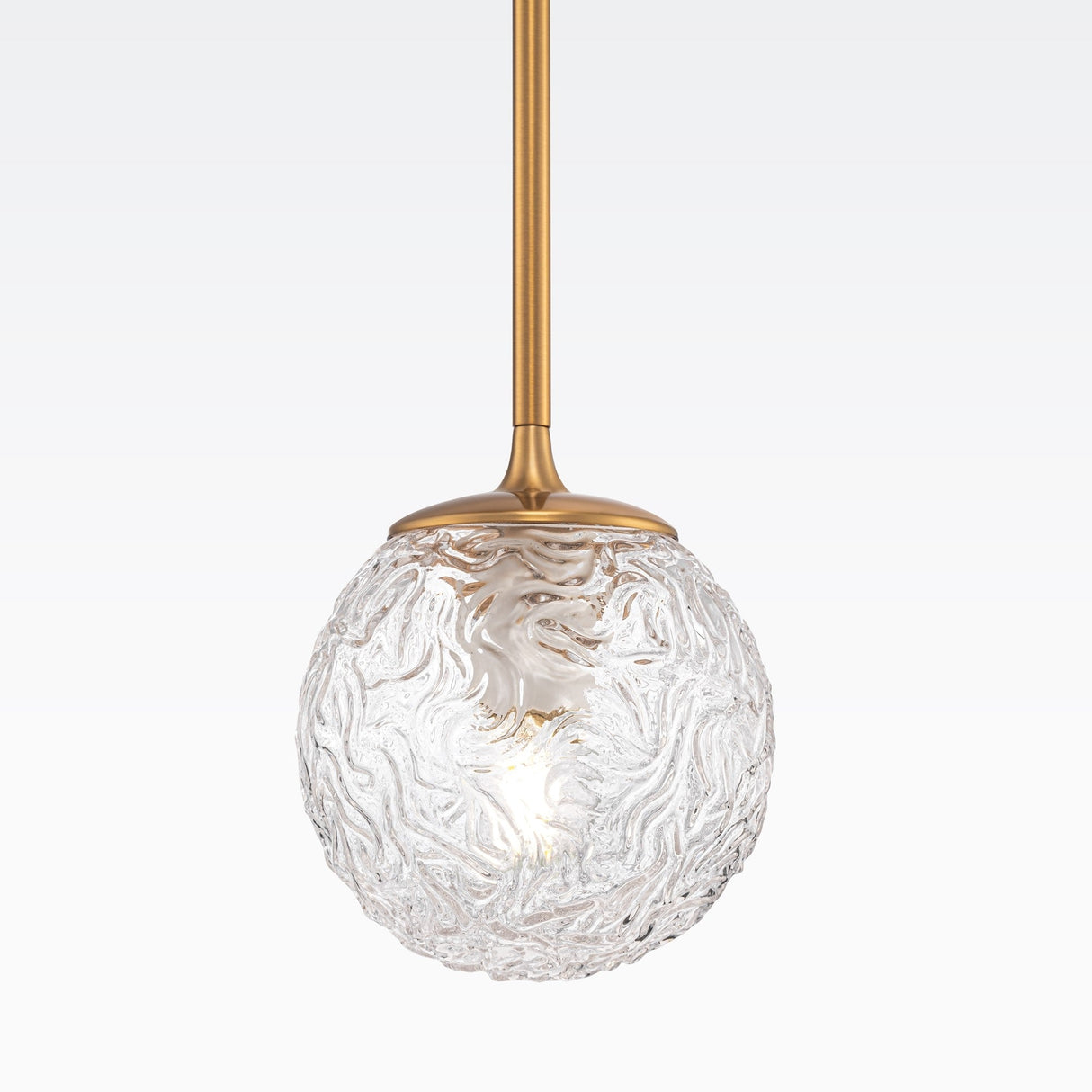 The Ligero Pendant Light - Brass With Clear Moire Glass features a spherical design with swirling texture, adjustable height, and emits a soft glow through its intricate pattern against a light gradient backdrop.