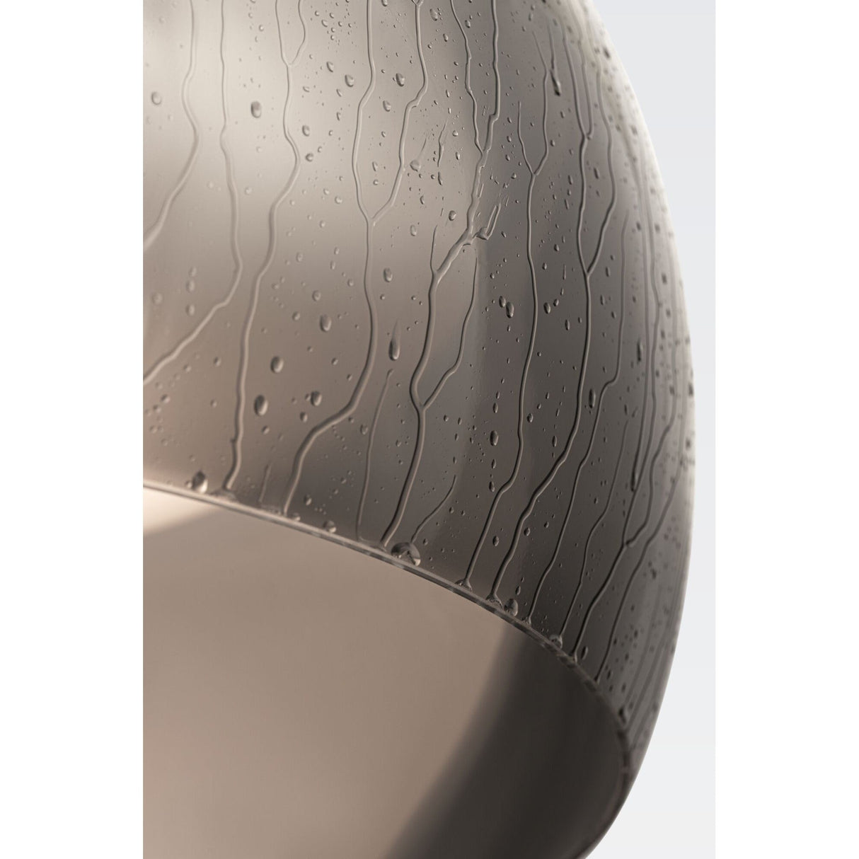 The Solen LED Pendant features a close-up of its black glass dome, showcasing raindrop-like patterns on the curved surface. The droplets streak downwards, evoking the textured aesthetic of industrial design, with a subtle glow beneath akin to a smoky glass dome.