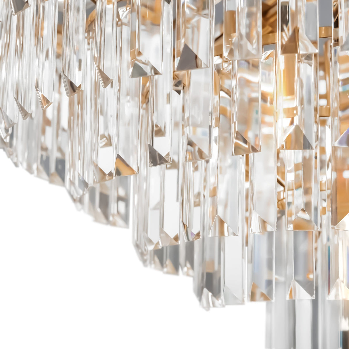 Close-up of the Revero 16 Light Chandelier - Brass, showcasing its intricate hanging crystal prisms. The angle highlights the clarity and detailed design of the crystal pendants, reflecting and refracting light against a white background.