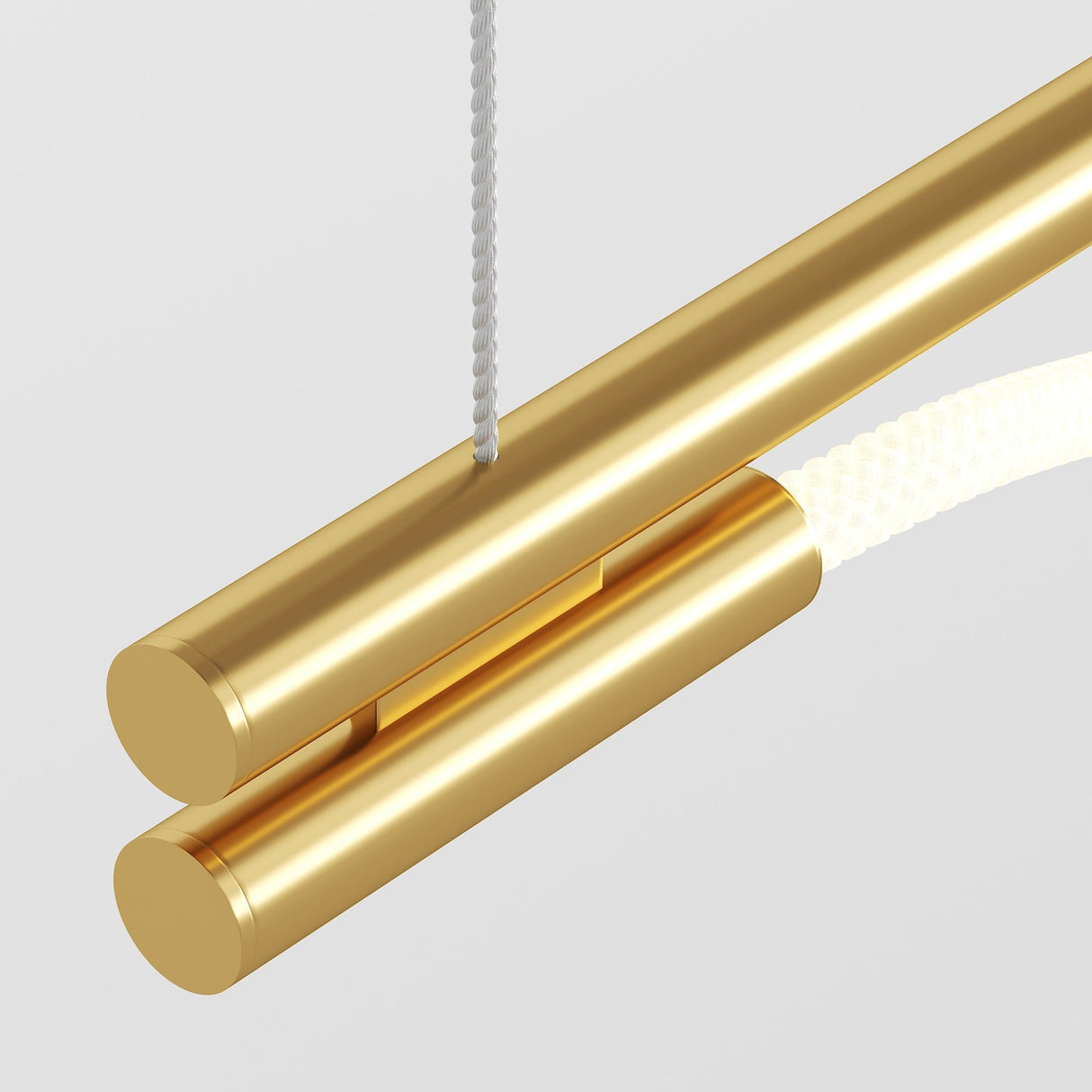 A close-up of the Tau LED Long Linear Suspension Light 3000K 30W - Gold showcases its modern design, with two parallel cylindrical tubes and a braided cord at the top. The minimalist piece features sleek metallic surfaces set against a light gray background.