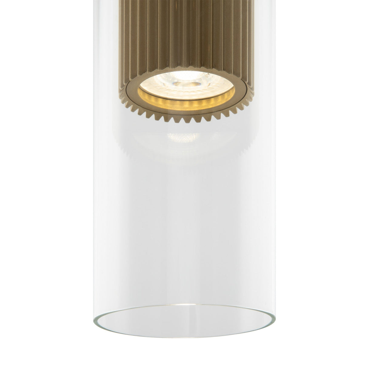 A close-up shot of the Dynamics Pendant Light - Gold With Outer Clear Glass, featuring a sleek cylindrical design with a ribbed gold-finish interior. The visible bulb emits a soft glow, embodying the elegance and minimalist charm of contemporary lighting.