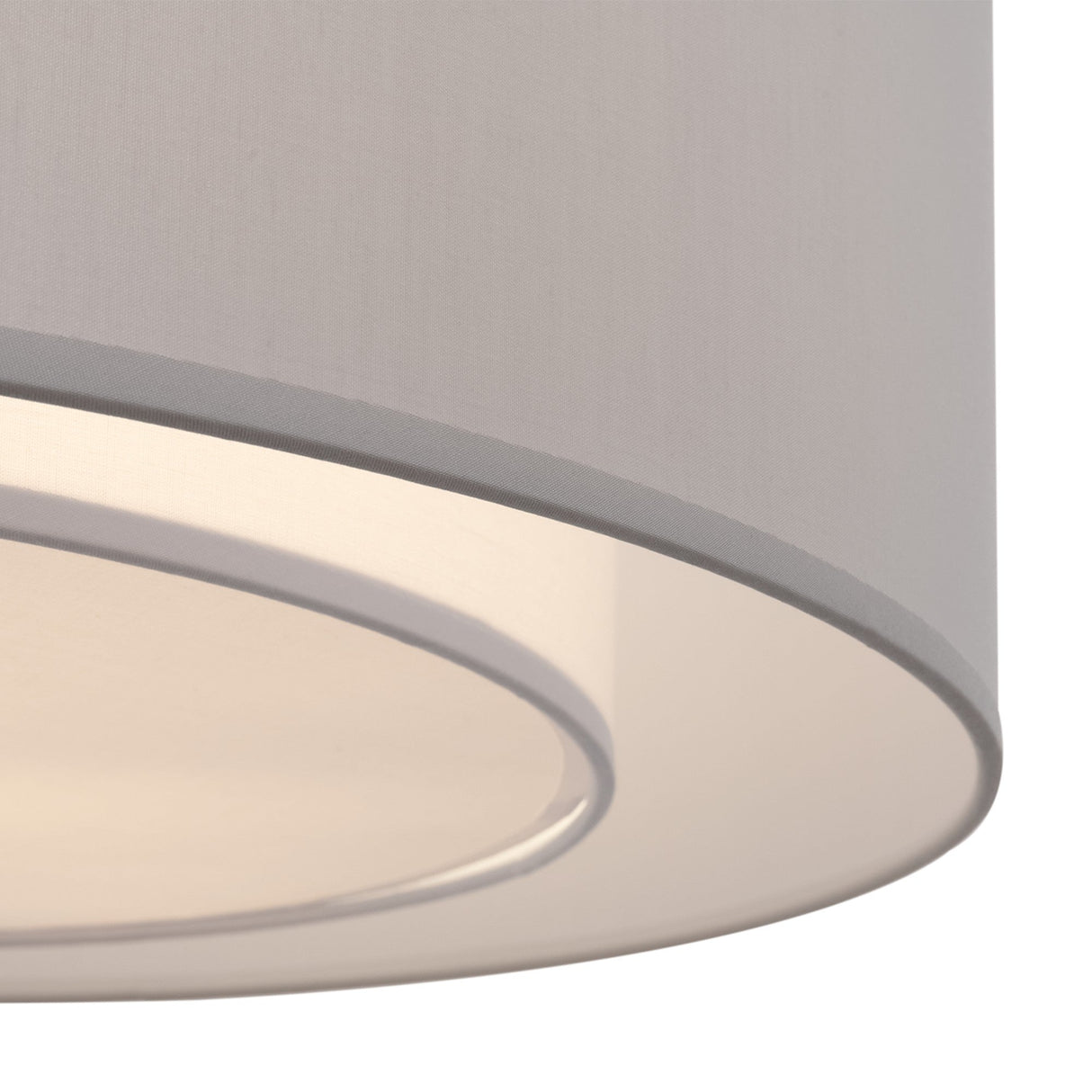 A close-up of a round white fabric lampshade with a chrome frame reveals soft light highlighting its texture. The inward-curving edge creates layers reminiscent of the Bergamo 3 Light Flush design in Chrome with White & Grey Shade.