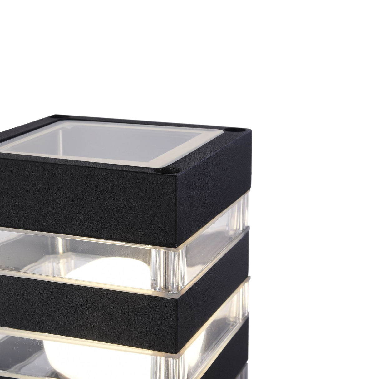 The Unter den Linden Bollard Light - Black features a sleek, corrosion-resistant square design with transparent sections revealing a glowing bulb inside. Its an ideal choice for stylish outdoor lighting solutions.