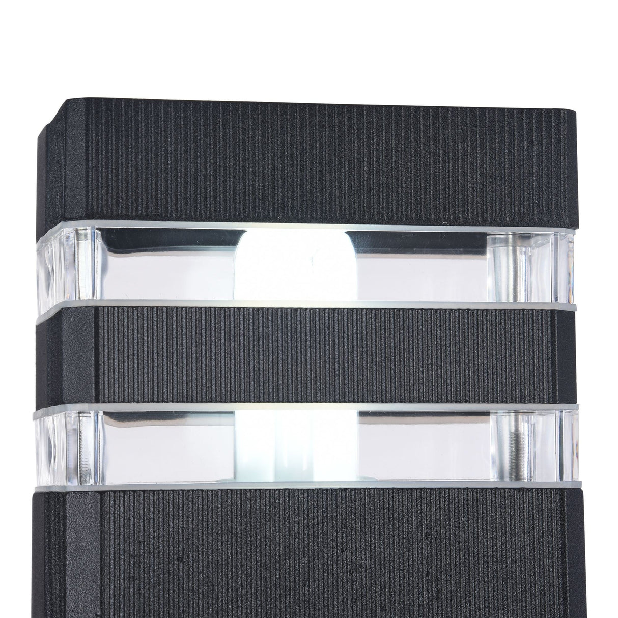 A close-up of the Unter den Linden Outdoor Wall Light - Black reveals its modern aluminium body with a textured finish. Layered horizontal bands provide a contemporary design, and transparent panels emit bright white light. Its IP54 rating ensures it withstands the elements beautifully.