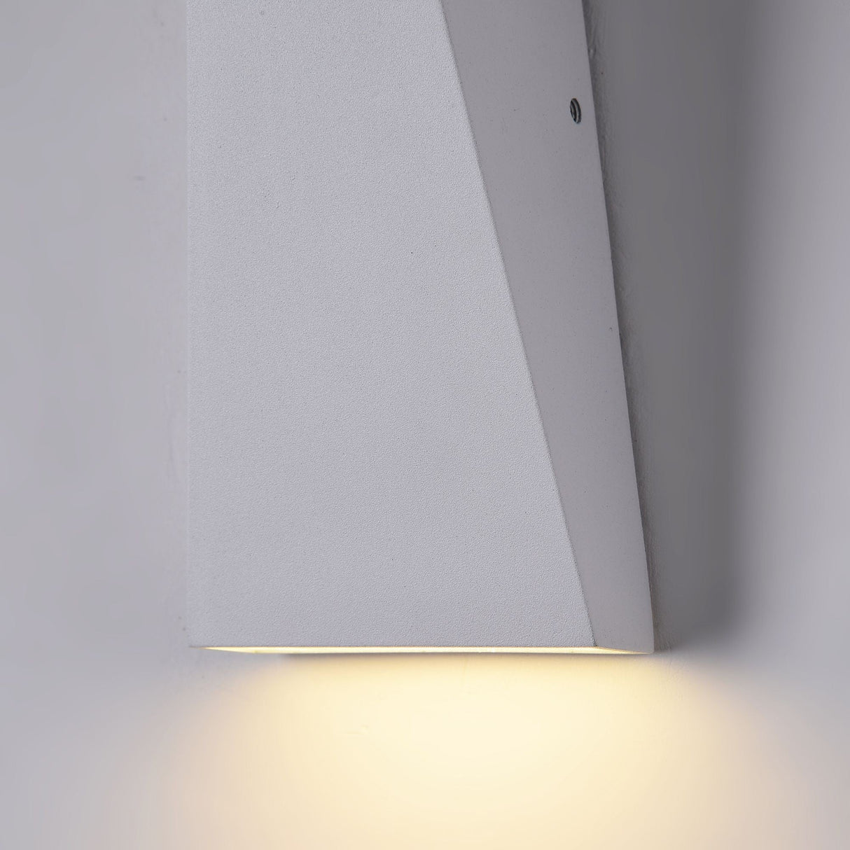 The Times Square Outdoor Wall Light 3200K 6W - White features a minimalist, geometric design. Made of light grey material, this IP54-rated fixture emits a warm glow downward, gently illuminating walls.