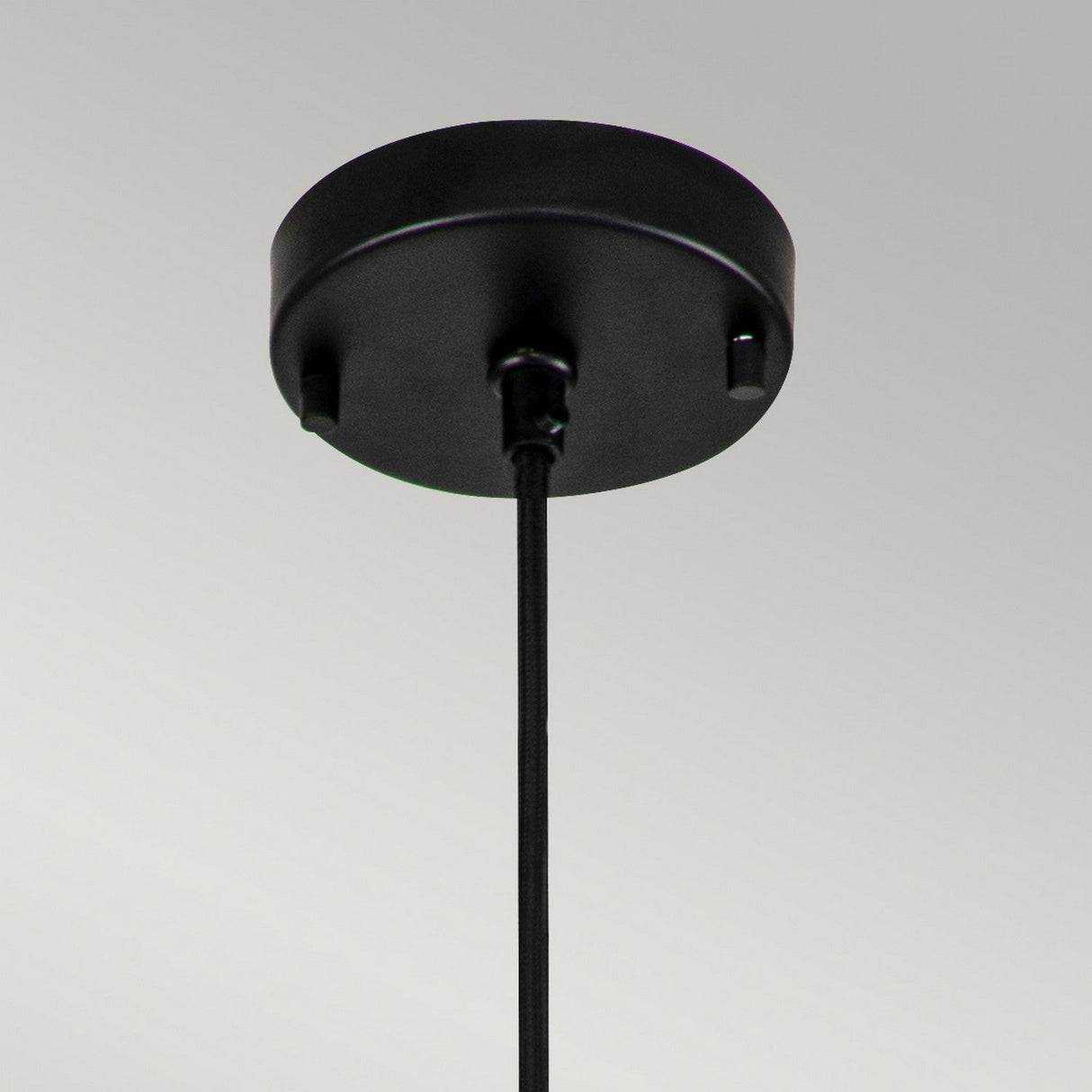 Close-up view of the Etoile 1 Light Medium Pendant - Matte Black, a ceiling fixture with a cylindrical canopy and a single cord extending downward against a plain background, showcasing an elegant star-shaped design.