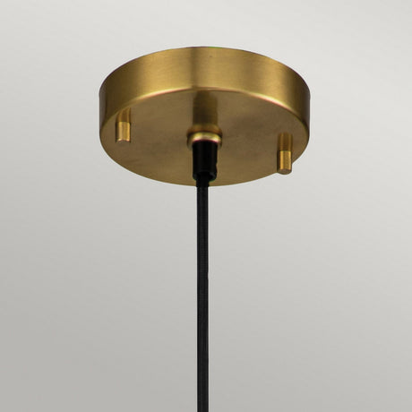 The Etoile 1 Light Small Pendant Light in aged brass features a round, metallic design with an adjustable black cord, set against a plain white background.