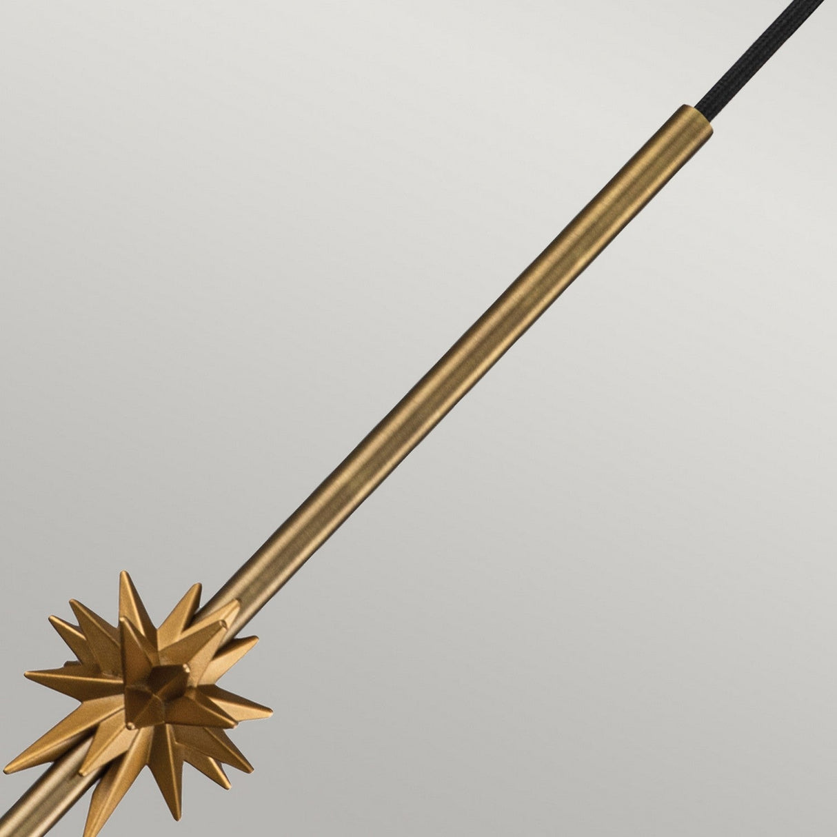 Aged brass finish Etoile 1 Light Small Pendant Light featuring a metallic wand design with a ridged handle and spiked star-shaped ornament adorned in gold, highlighted against a plain, light background.