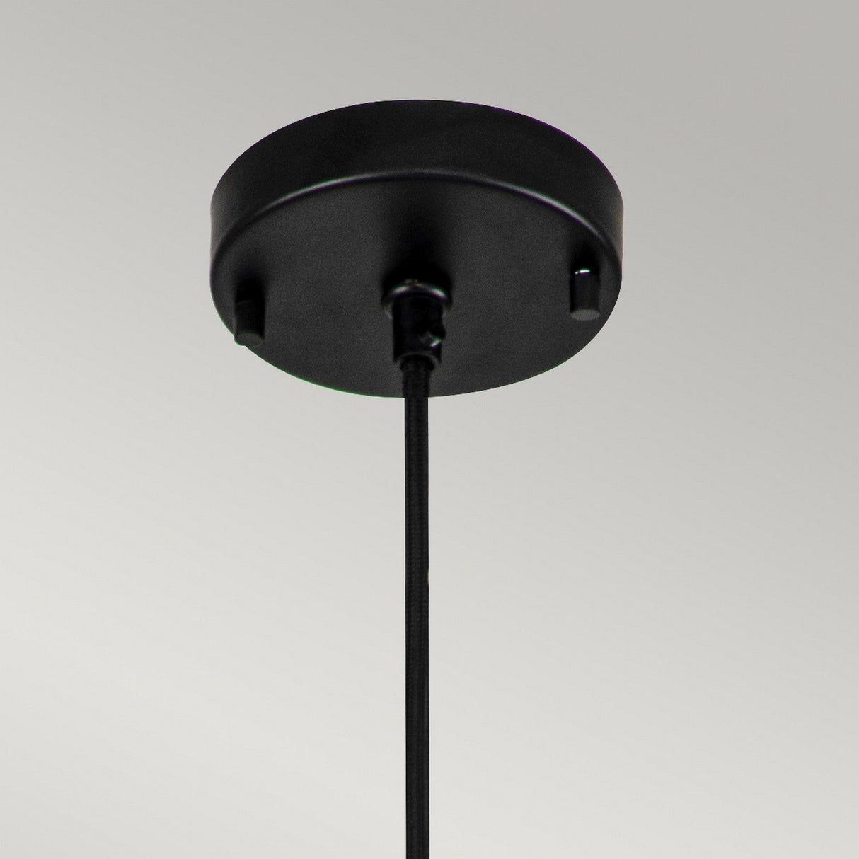 The Etoile 1 Light Small Pendant in Matte Black showcases a sleek design with its minimalist round canopy and downward cord, set against a light gray background, enhancing its modern lighting fixture appeal.