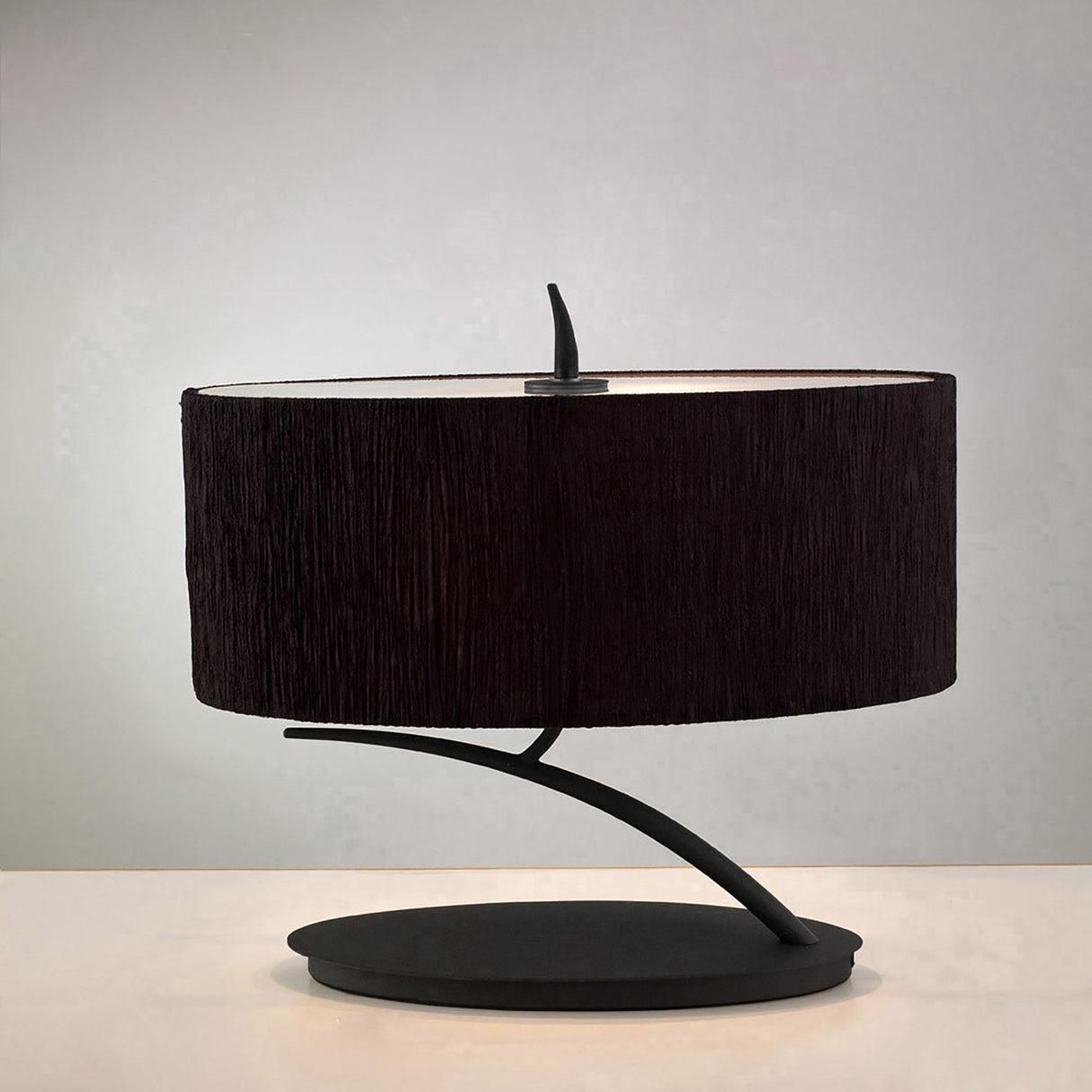 The Eve 2 Light Table Lamp - Anthracite With Black Oval Shade features a curved, minimalist anthracite metal base and a wide black oval shade, displayed on a plain white surface against a neutral background.