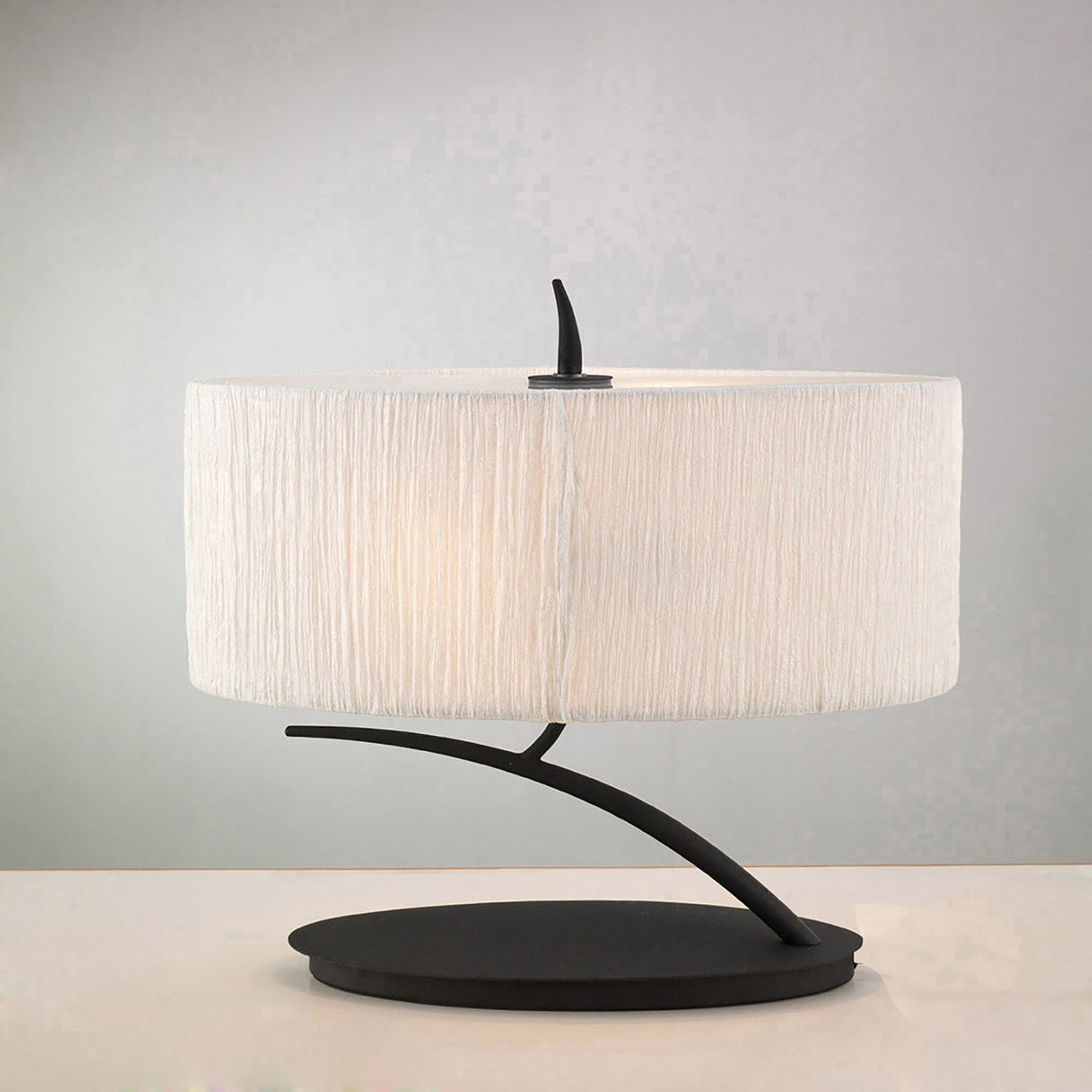 The Eve 2 Light Table Lamp features an anthracite curved base and a large white oval fabric shade, adding modern style to any space. Displayed on a white surface with a light gray background.