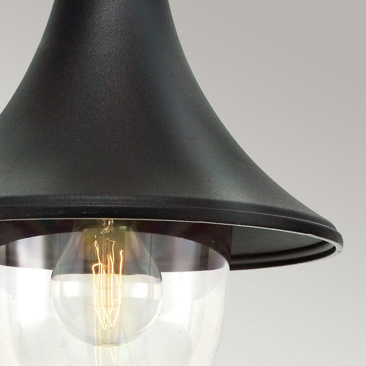 A detailed view of the Firenze Outdoor 1 Light Chain Pendant in black, featuring a conical shape and an IP54 Rating, shows a clear glass enclosure with an exposed filament light bulb inside, set against a light gray background.